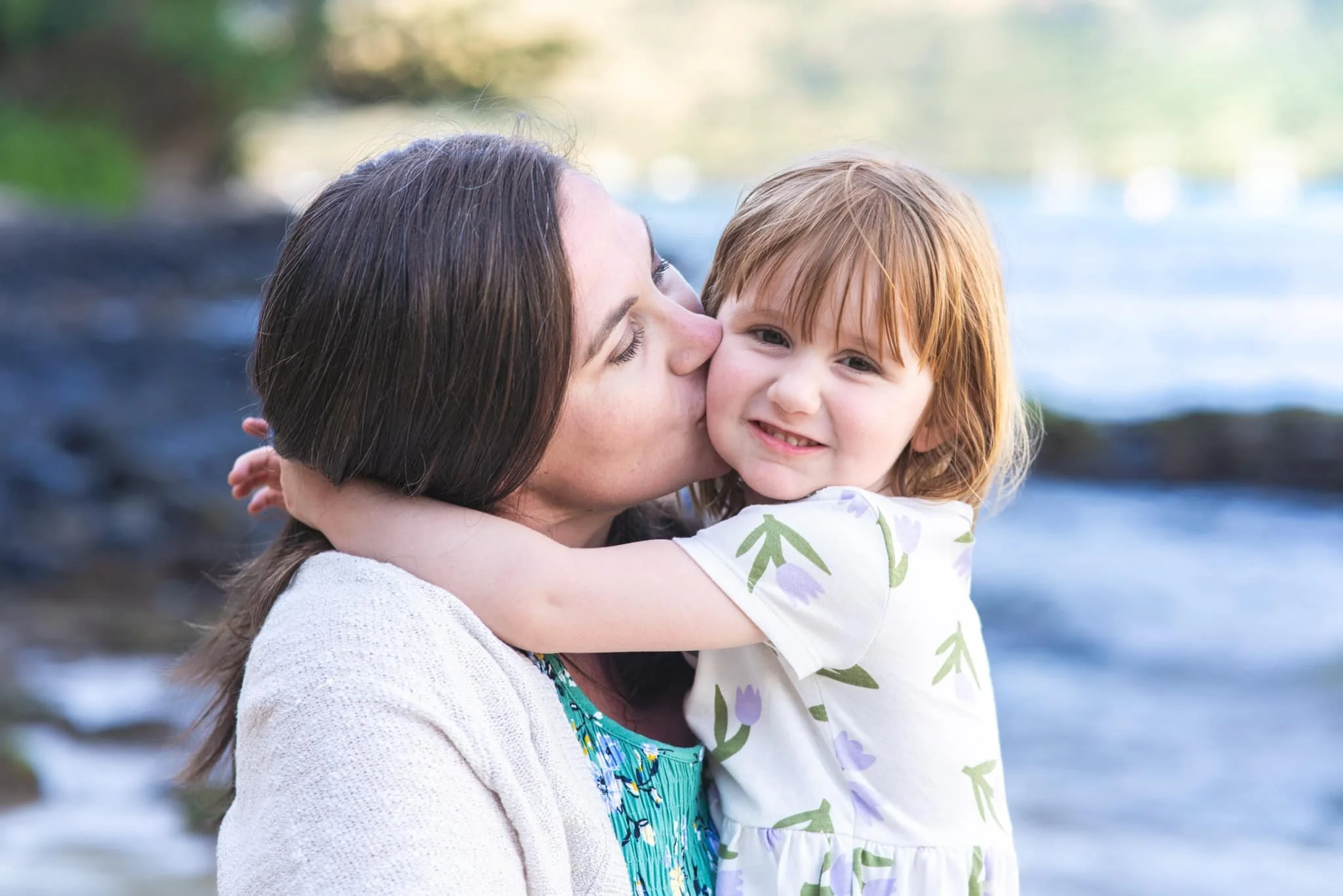 Mother kissing her young daughter's cheek during a Kauai family session.
