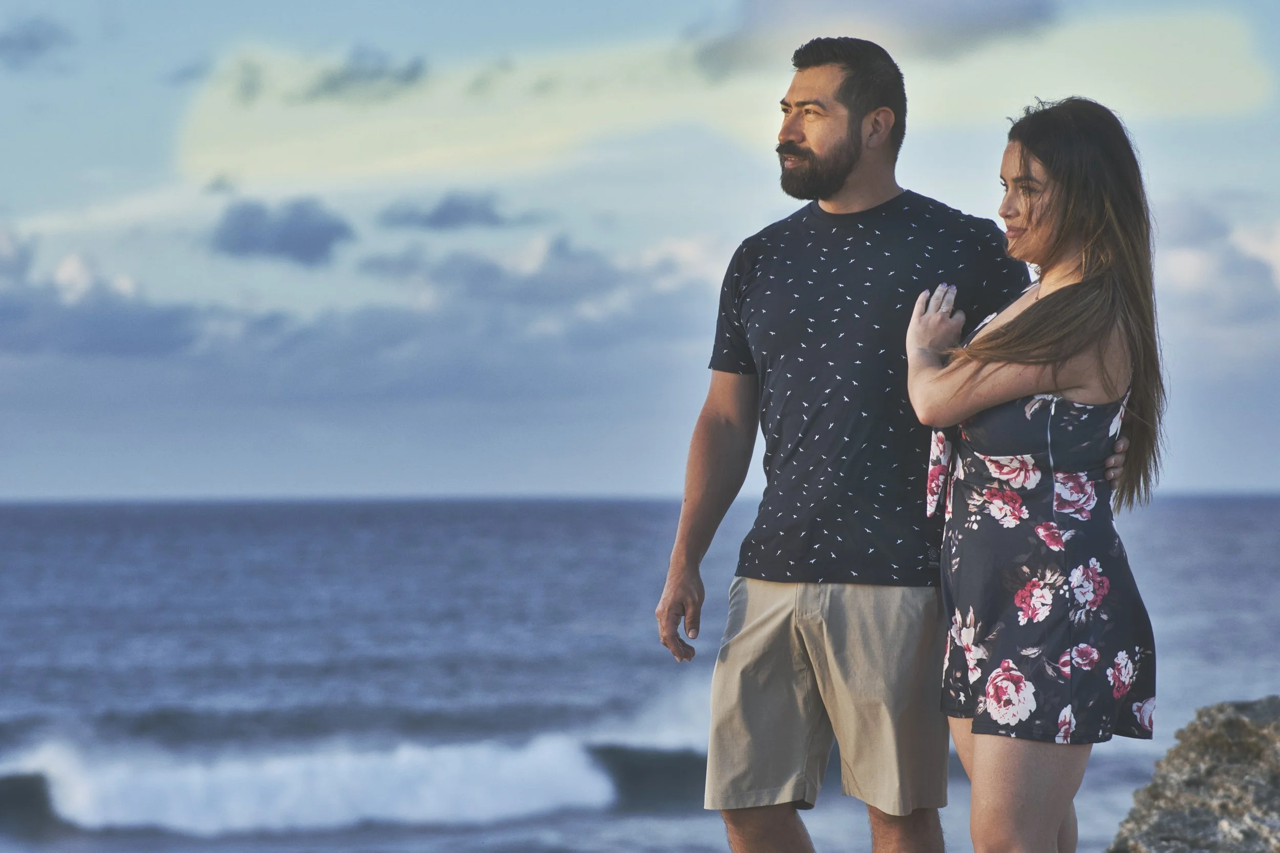 Couple standing together gazing at the ocean at Shipwreck Beach, Kauai.