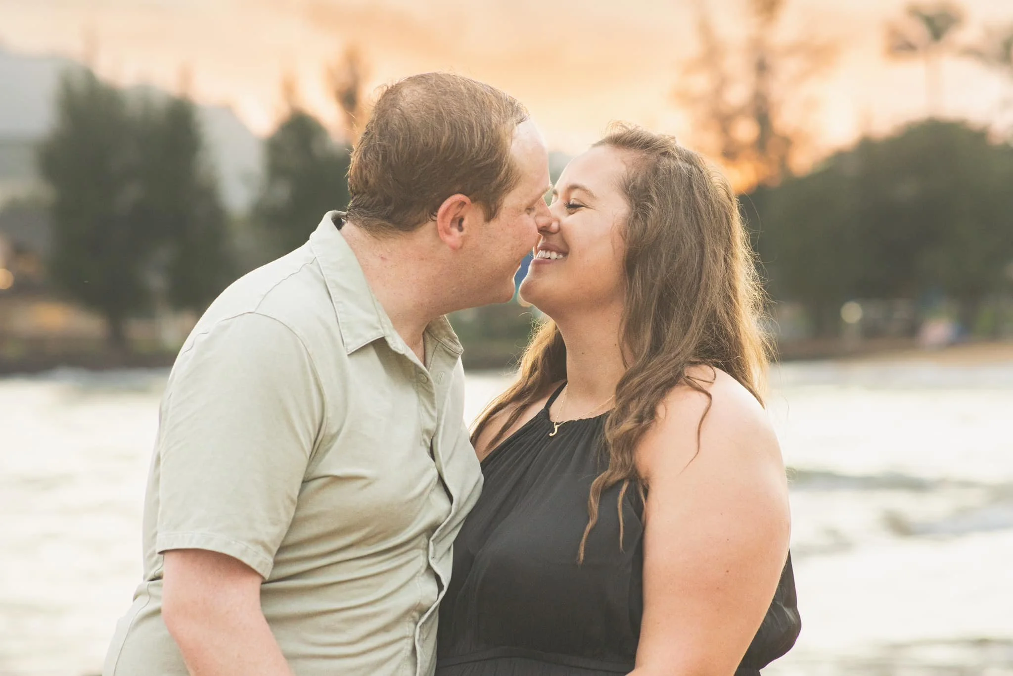 Couple sharing a tender nose-to-nose moment on a Kauai beach at sunset.