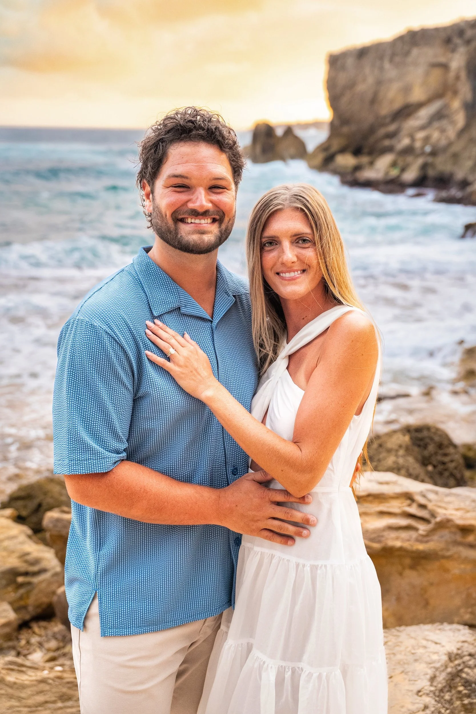 Smiling couple posing for a portrait on the rocky beach at Shipwreck Beach, Kauai.