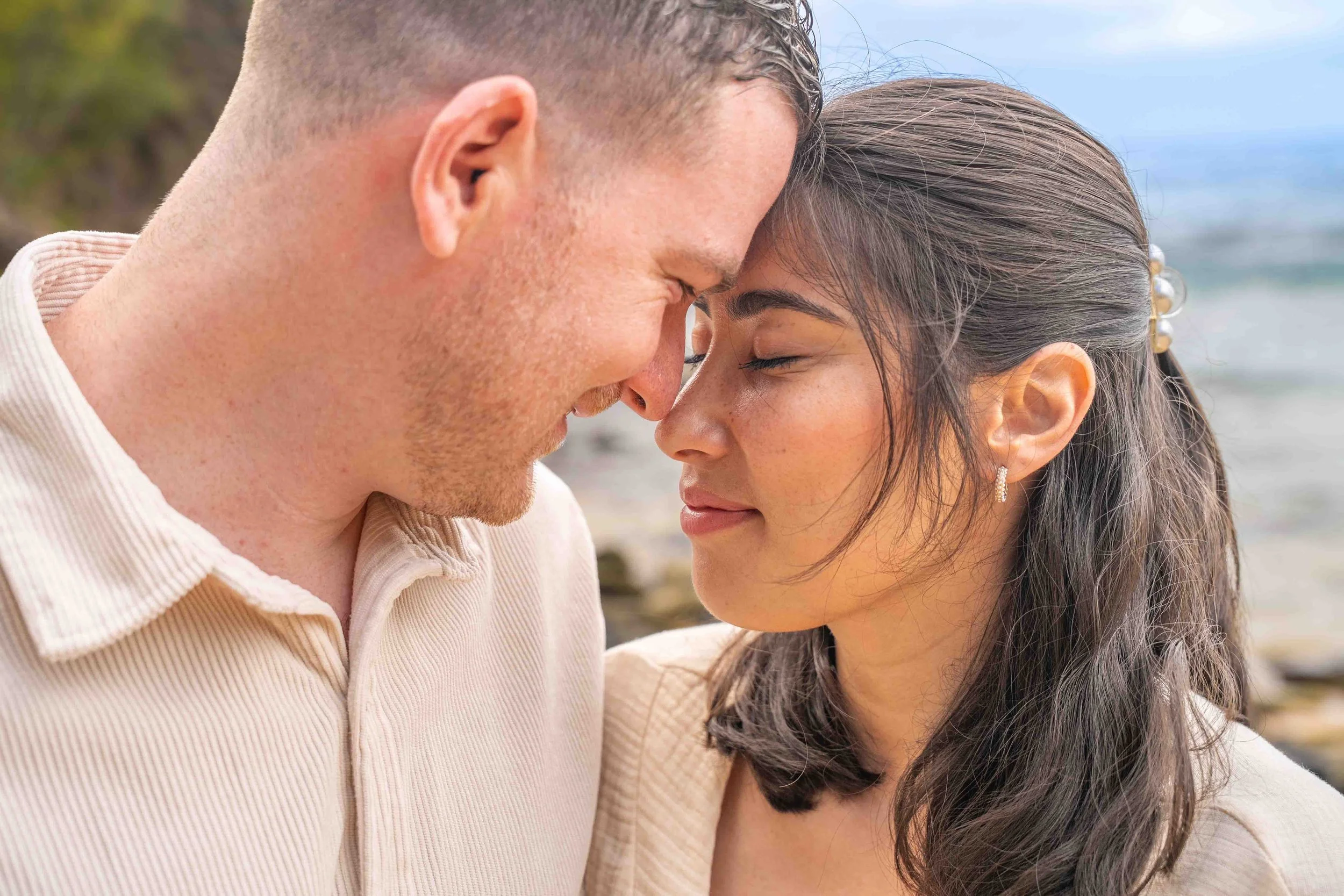 Couple touching foreheads with eyes closed on a Kauai beach.