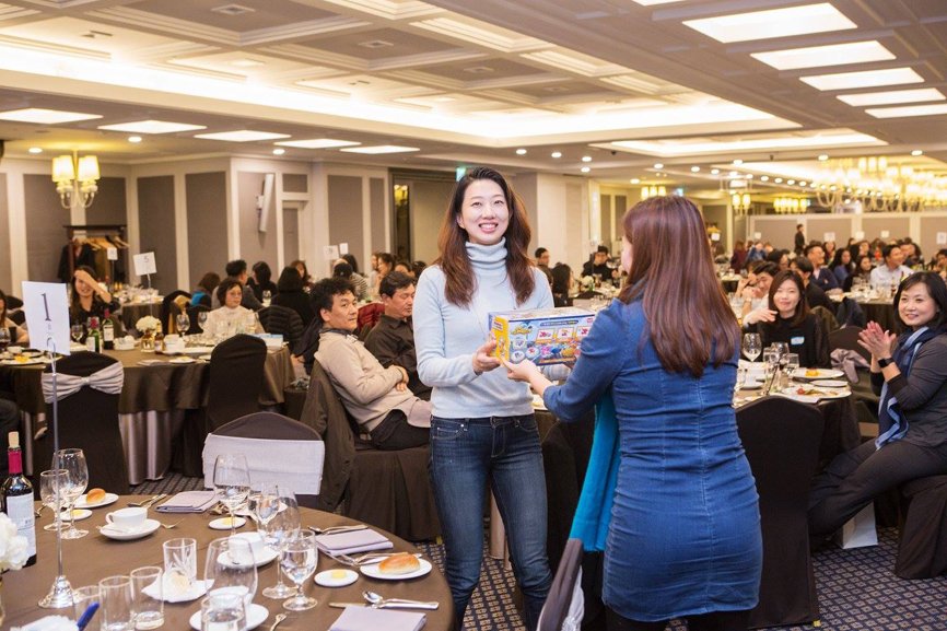 During the alumni event, one woman is receiving an award. Another woman is presenting her with a prize.