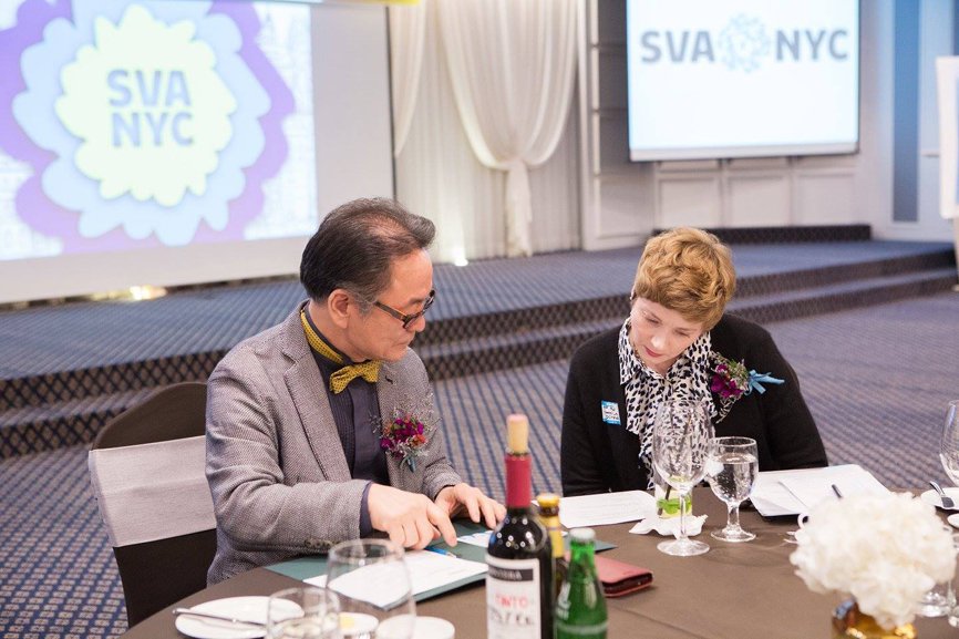Andrew Chang and Jane Nuzzo are seated at the round table, engrossed in a conversation while looking at documents.