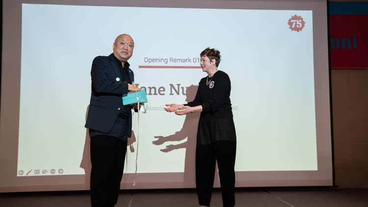 Former Alumni Association President Kim Tak-hoon and Alumni Affairs Director Jane Nuzzo are posing together on the stage. The screen displays "Alumni Affairs Director Jane Nuzzo."