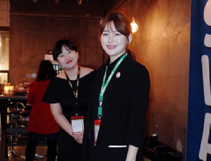 There are two women wearing black clothing. Both of them have name tags hanging around their necks.