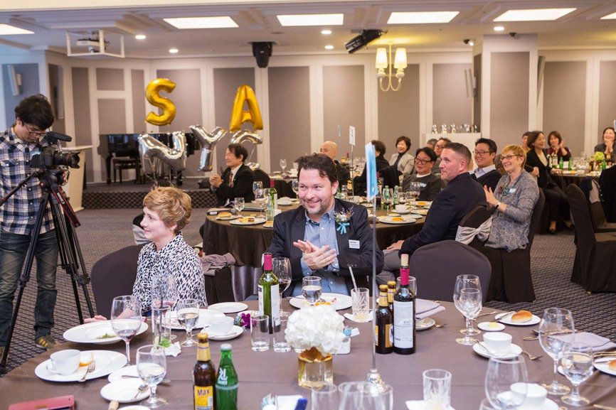 During the alumni party, people are applauding while looking at the stage.