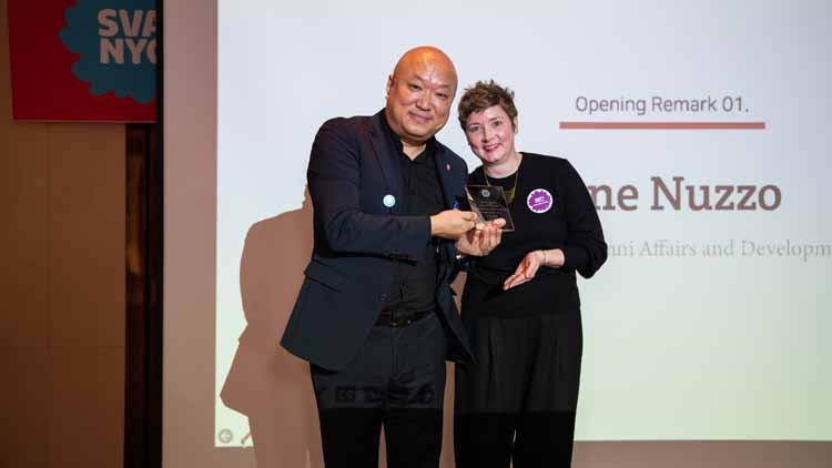 Former Alumni Association President Kim Tak-hoon and Alumni Affairs Director Jane Nuzzo are posing together on the stage. The screen displays "Alumni Affairs Director Jane Nuzzo."