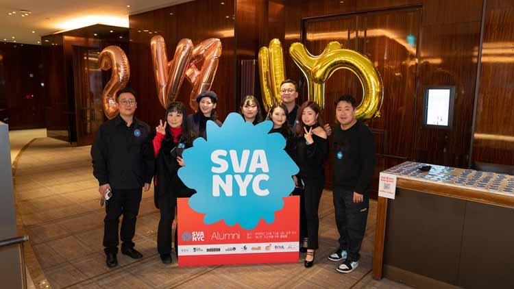 There are 8 males and females gathered around a blue signboard that says "SVA NYC," striking poses. .