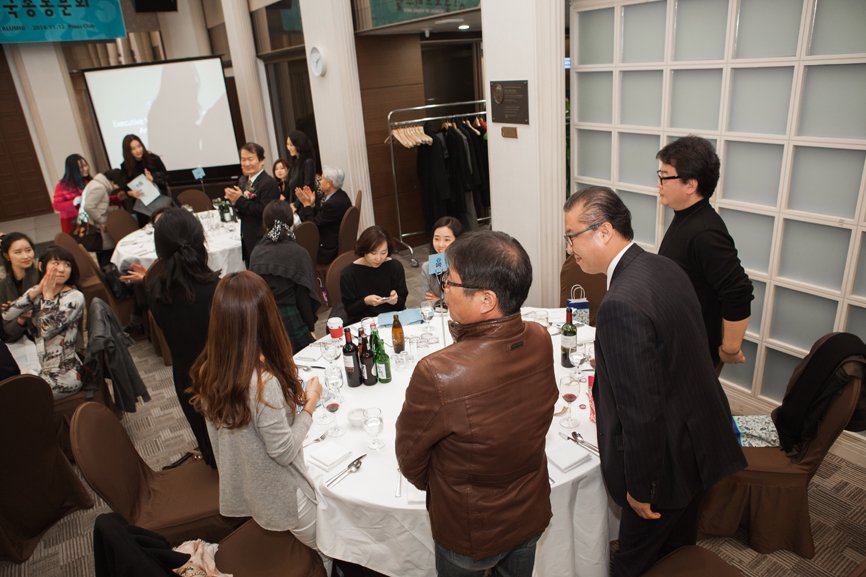 Amidst the alumni gathered around the round table, two men stand up and greet each other.