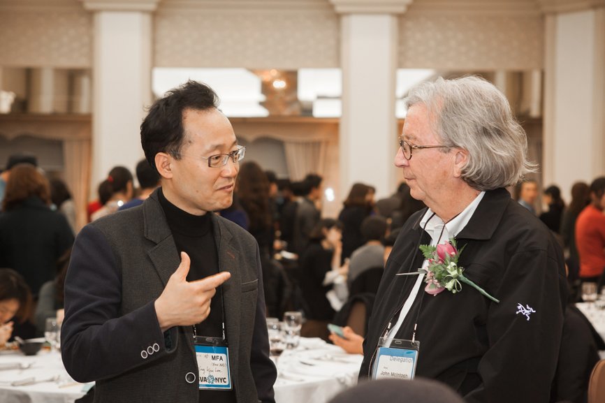 Two men at the alumni gathering are engaged in conversation with each other.