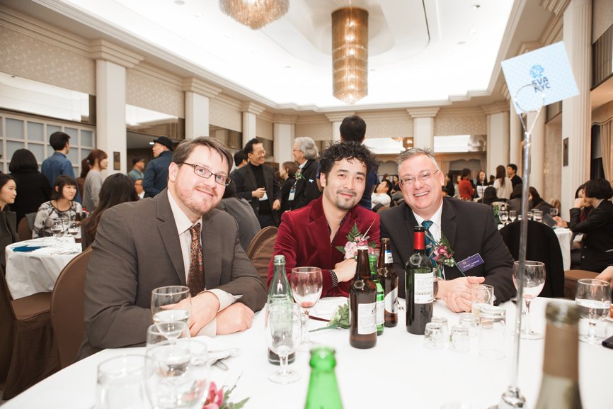 Adam, Renyi, and Michael are posing for the camera during the alumni gathering.