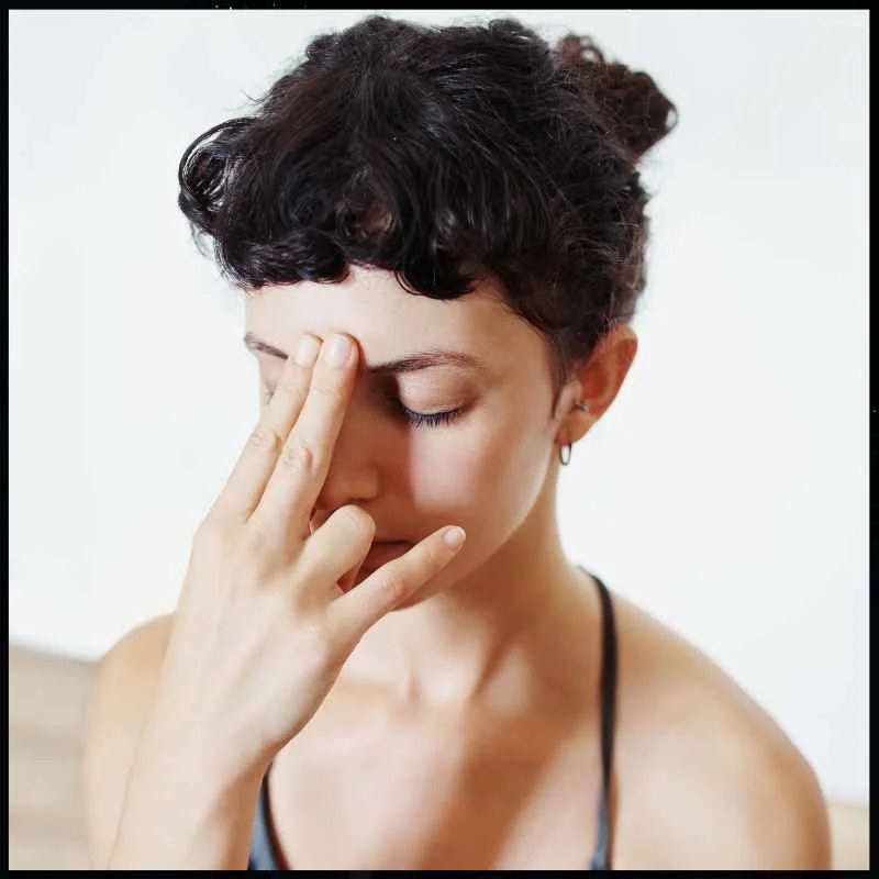 A young woman pressing two fingers on the area between the eyebrows