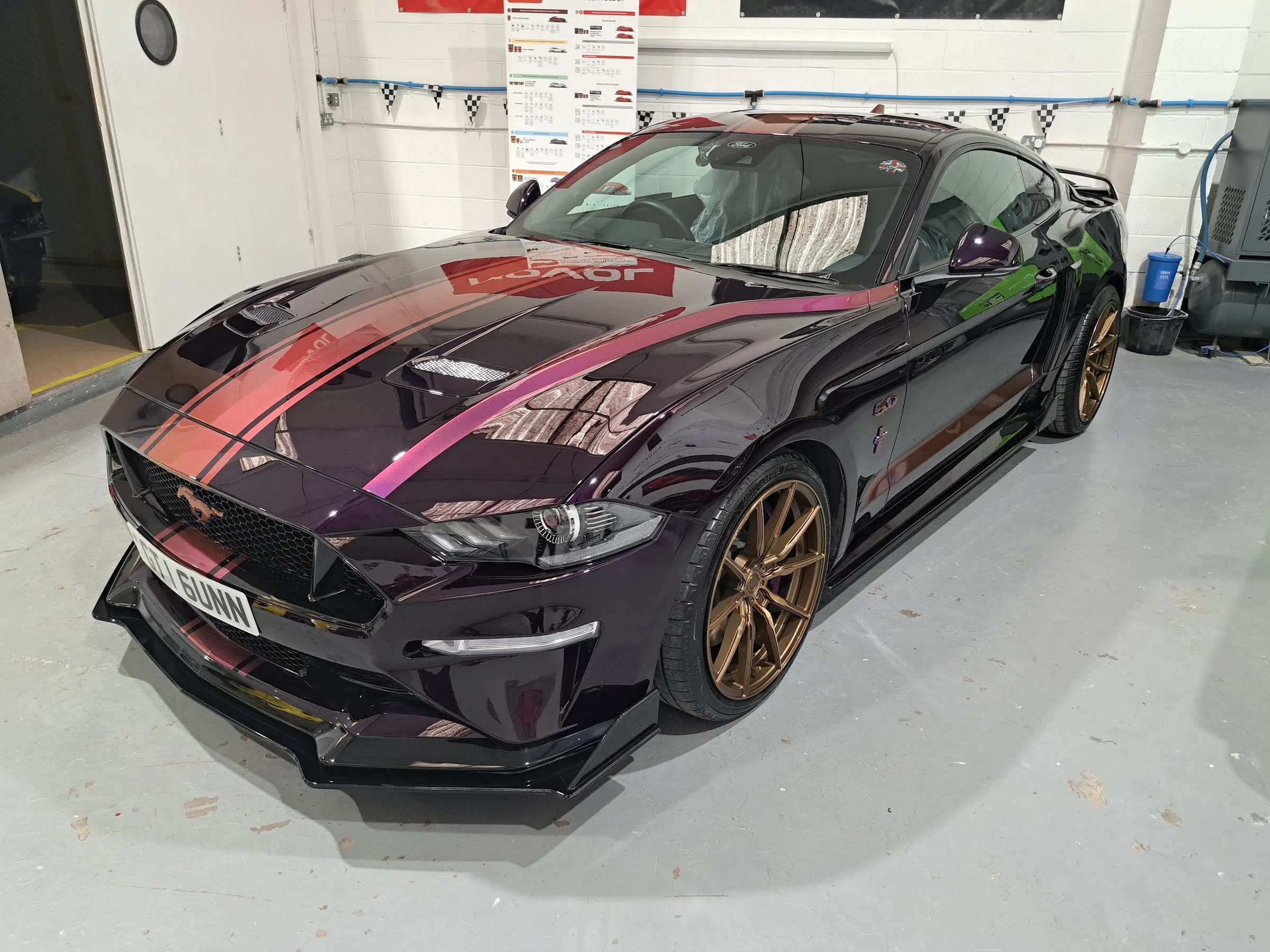 Dark Ford Mustang with multicoloured bonnet stripes