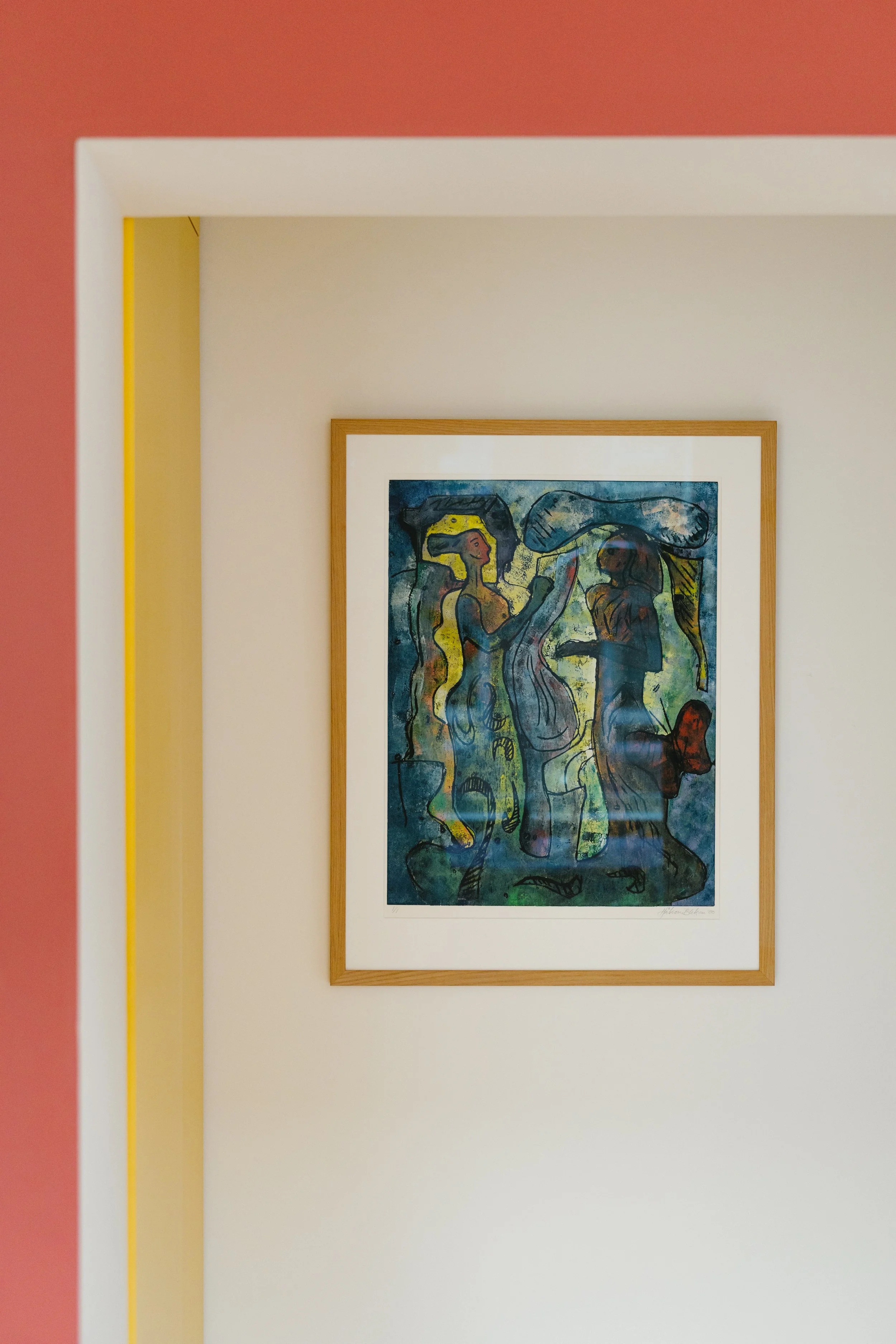 Colorful abstract painting of two women, with one playing a musical instrument, framed on a white wall in a room with pink and yellow walls.