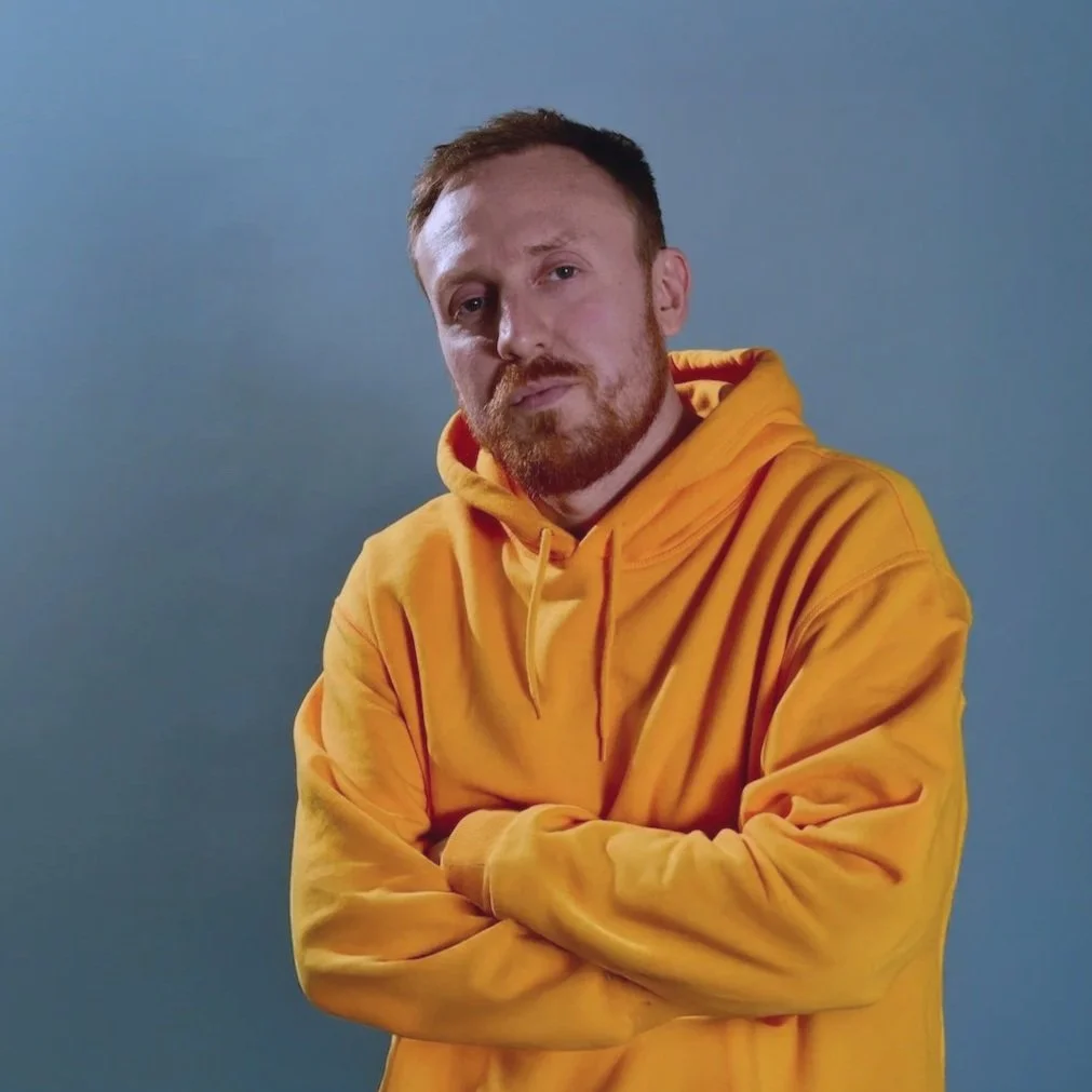 Studio portrait of Griogair wearing a yellow hoodie, 2018.