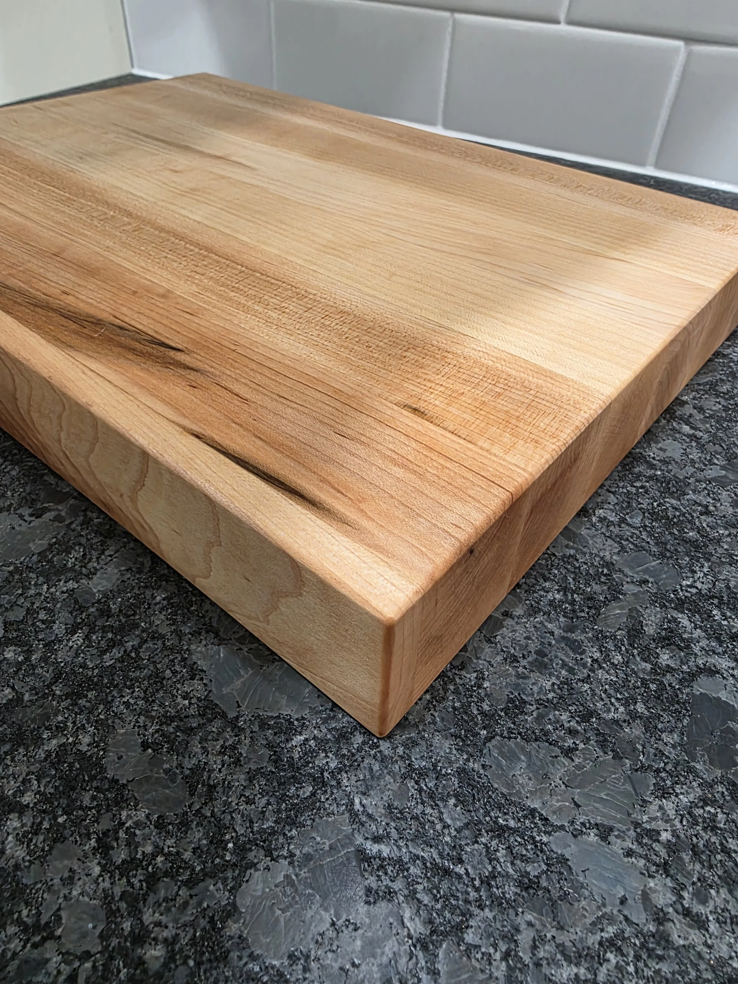 Solid maple edge grain cutting board close up of corner and natural wood grain.