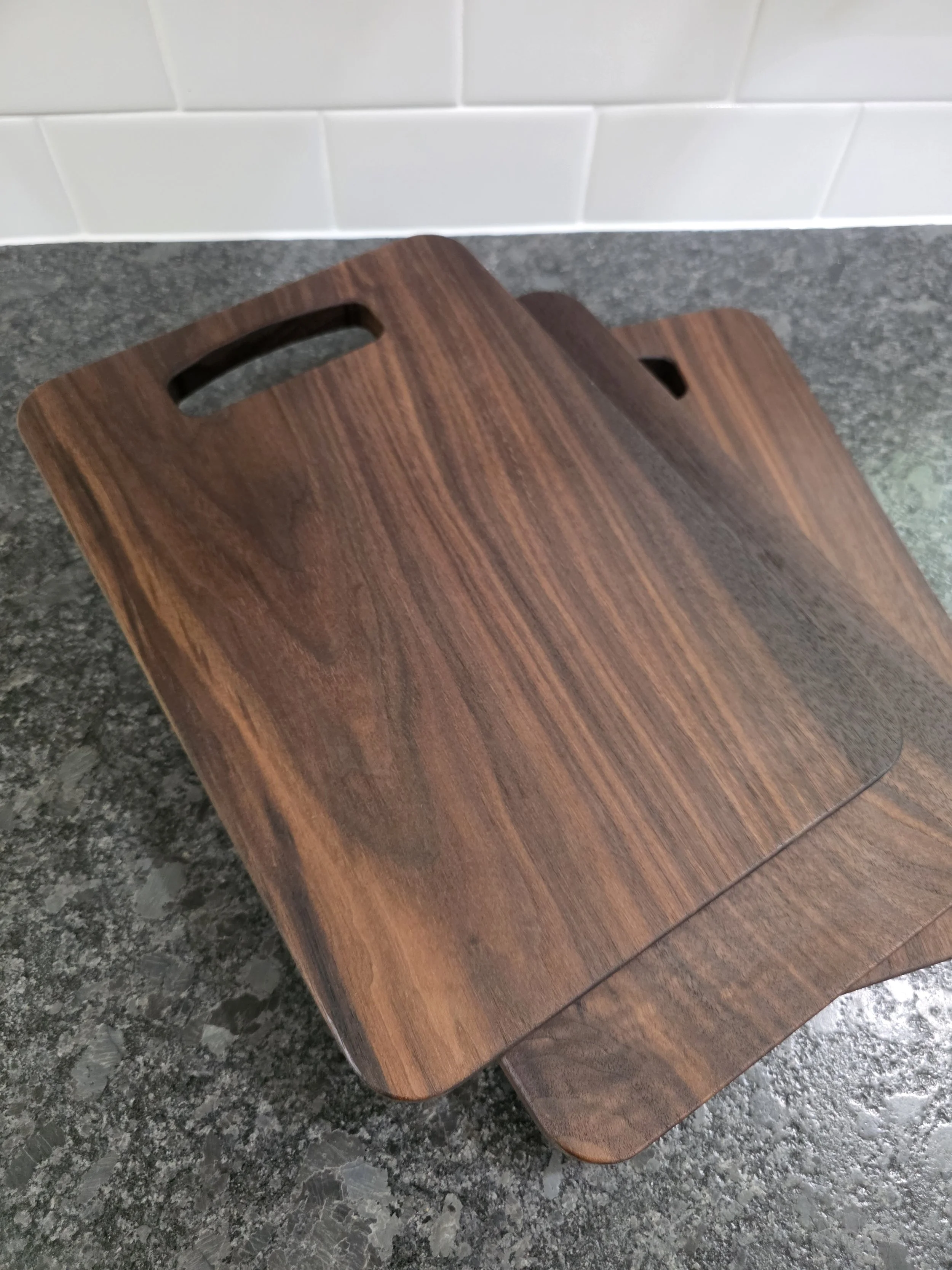 Multiple black walnut cutting boards stacked on counter.