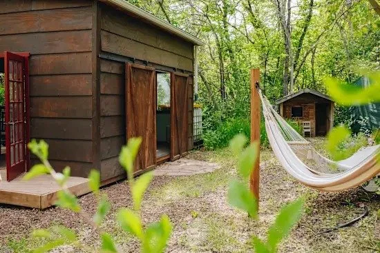 The Little B Creekside Heated Cabin with a hammock set among trees on the farm