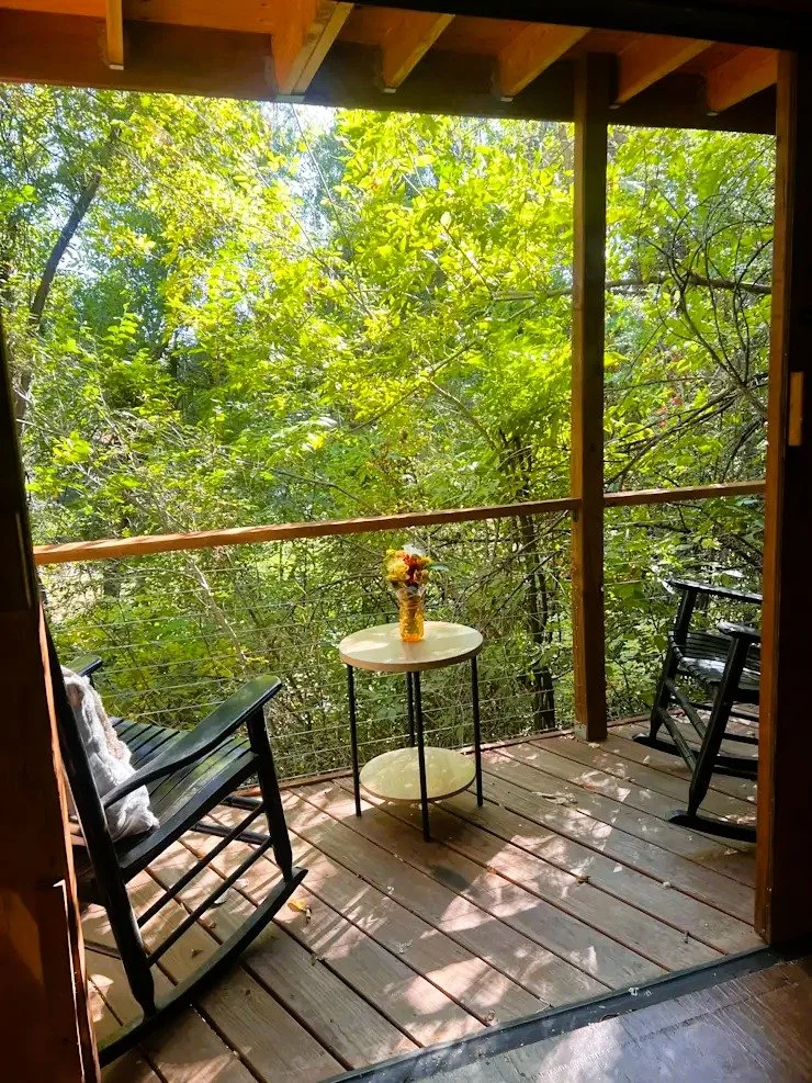 Covered deck at The Little B Creekside Heated Cabin overlooking trees and greenery.