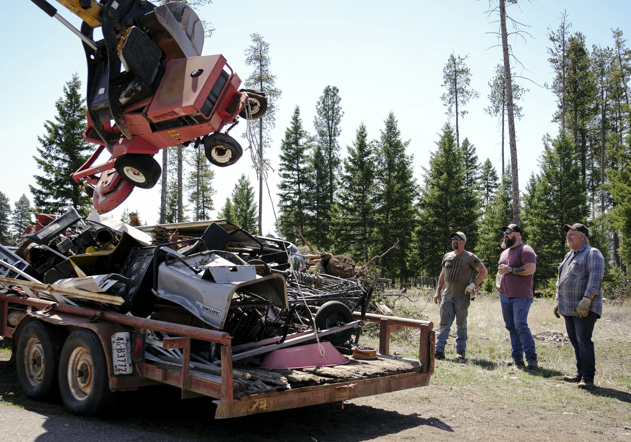 A group of guys watch an old lawn mower get put into a trailer to be taken to the dump on May 3. Michelle Dunn helped to arrange a community clean up at Mike Lindermier's steakhouse, in attempts to clean up lots around town for those who can't affor