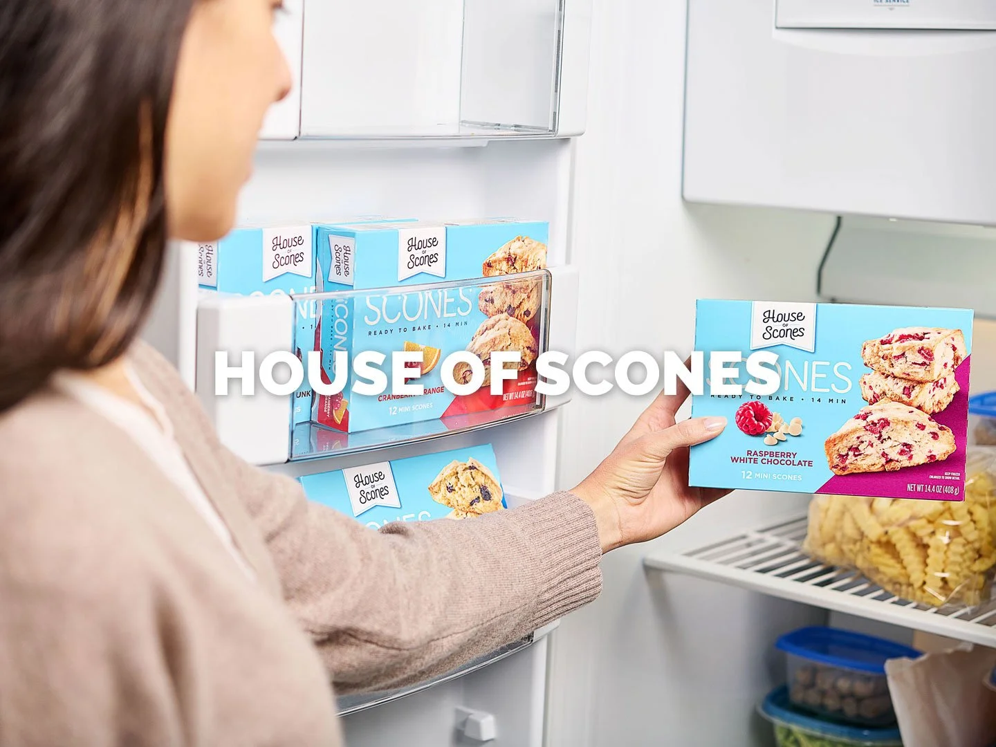A young woman pulls a box of House of Scones' raspberry-white chocolate scones from the freezer in this bright and inviting photo. This was a lifestyle food packaging photoshoot by Amy Roth for the client.