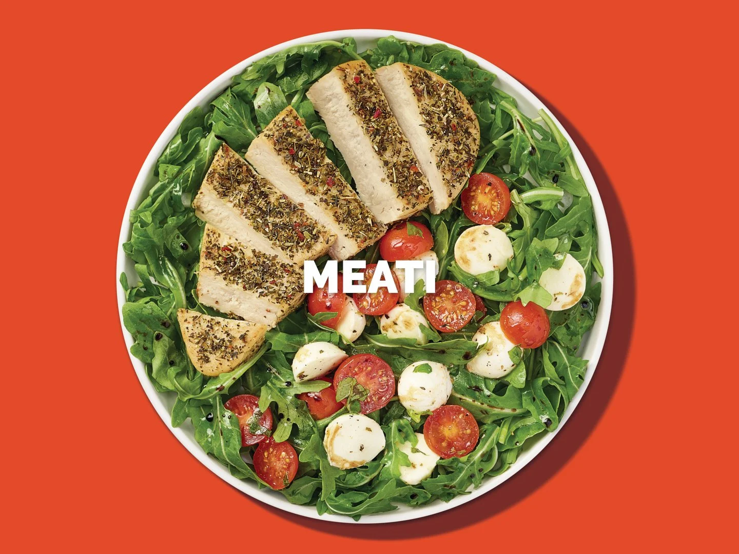 A vibrant food photography shot featuring a fresh arugula salad topped with a sliced Meati Italian-Seasoned Cutlet, a plant-based protein made from mushrooms. This image highlights the product’s herb-seasoned texture alongside cherry tomatoes and moz