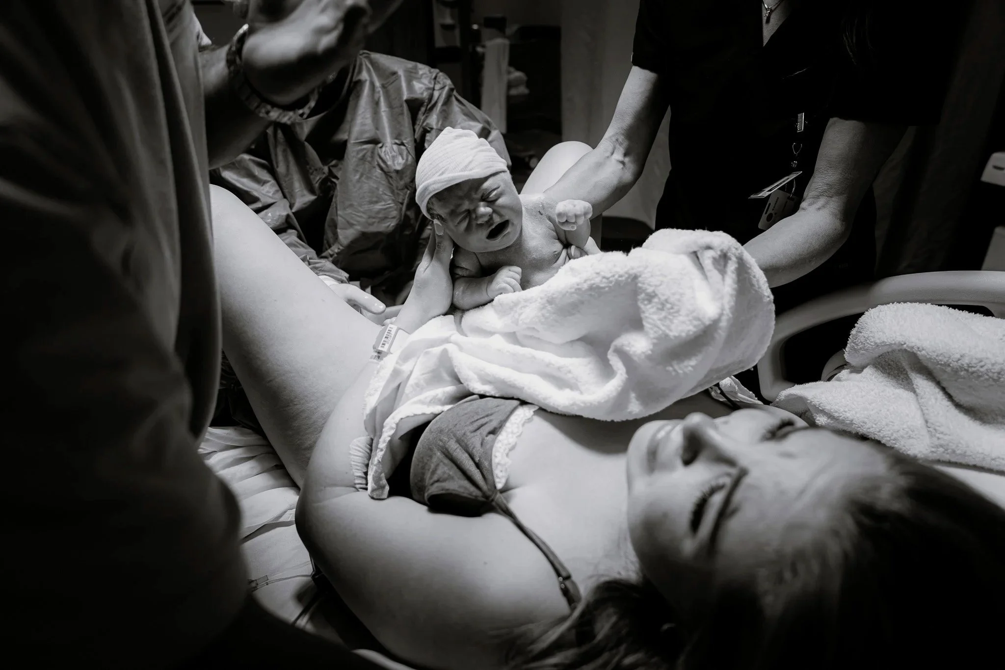 Baby being born in a hospital, surrounded by medical staff.