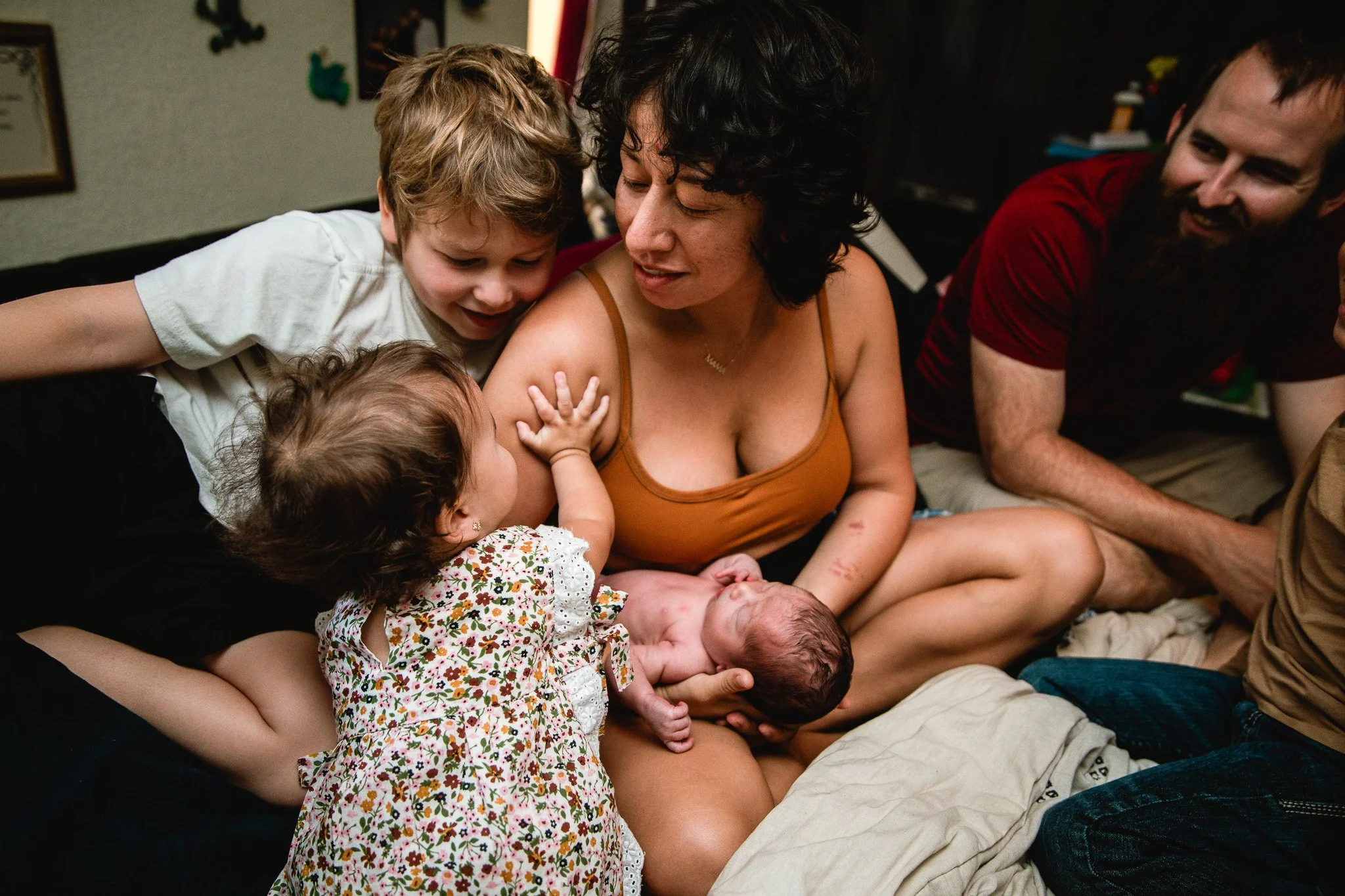 Family gathered around, celebrating a new baby in a cozy indoor setting.