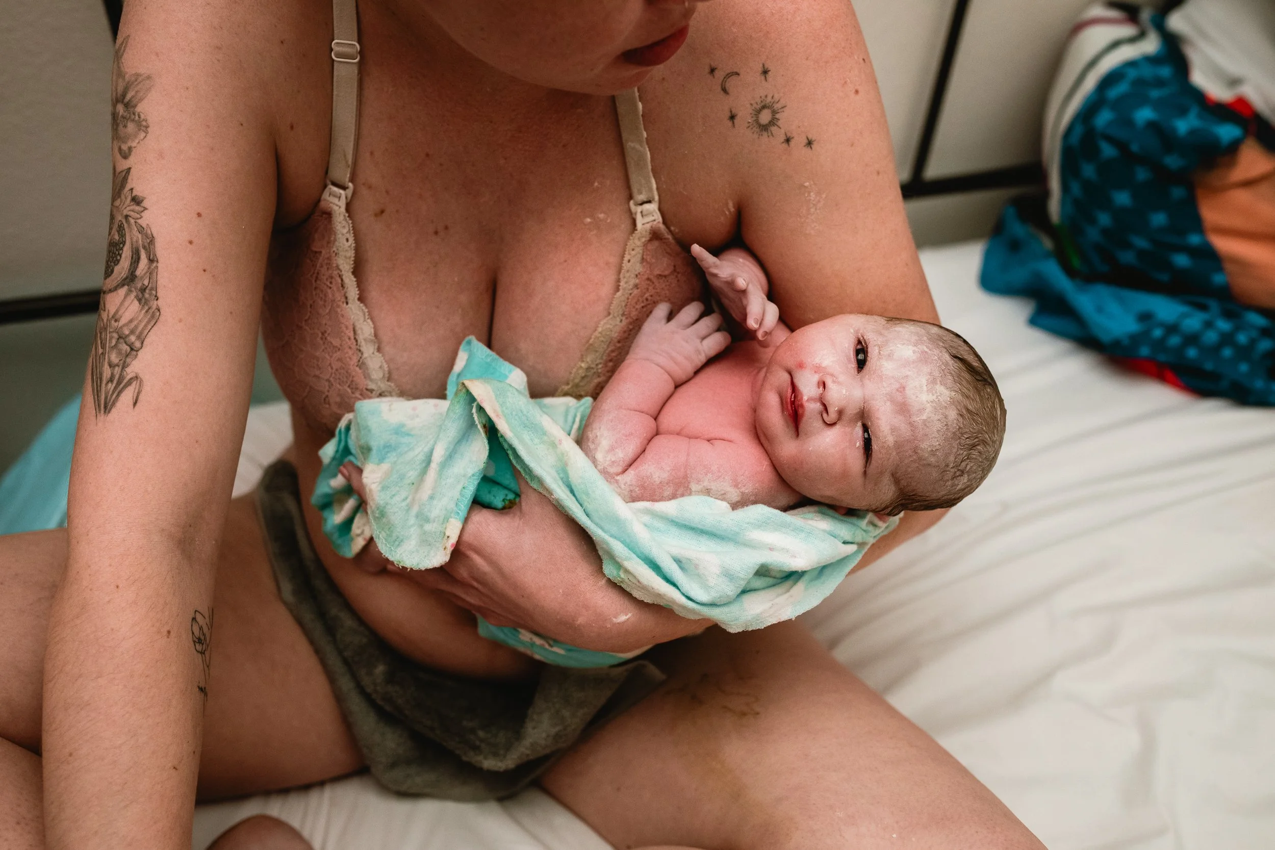 A woman holding a newborn baby in a hospital room.