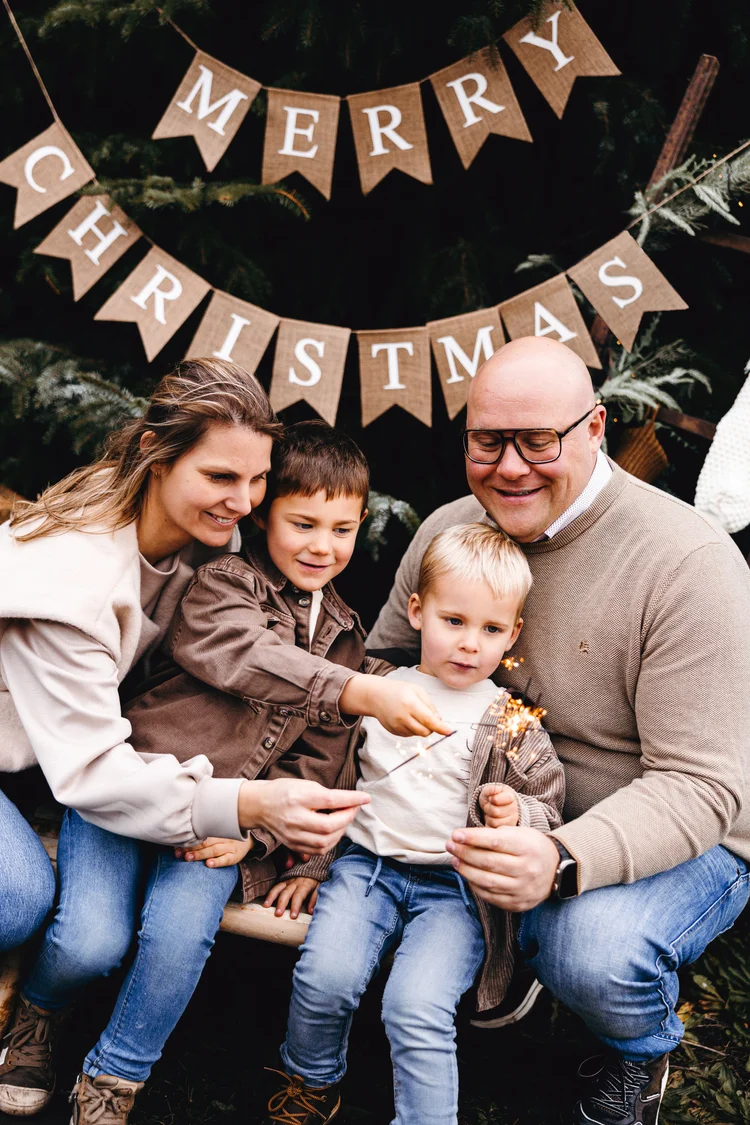 Gezin met sterretjes onder de Merry Christmas-slinger