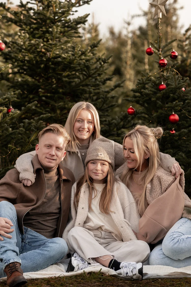Gezin samen op een deken tussen de kerstbomen