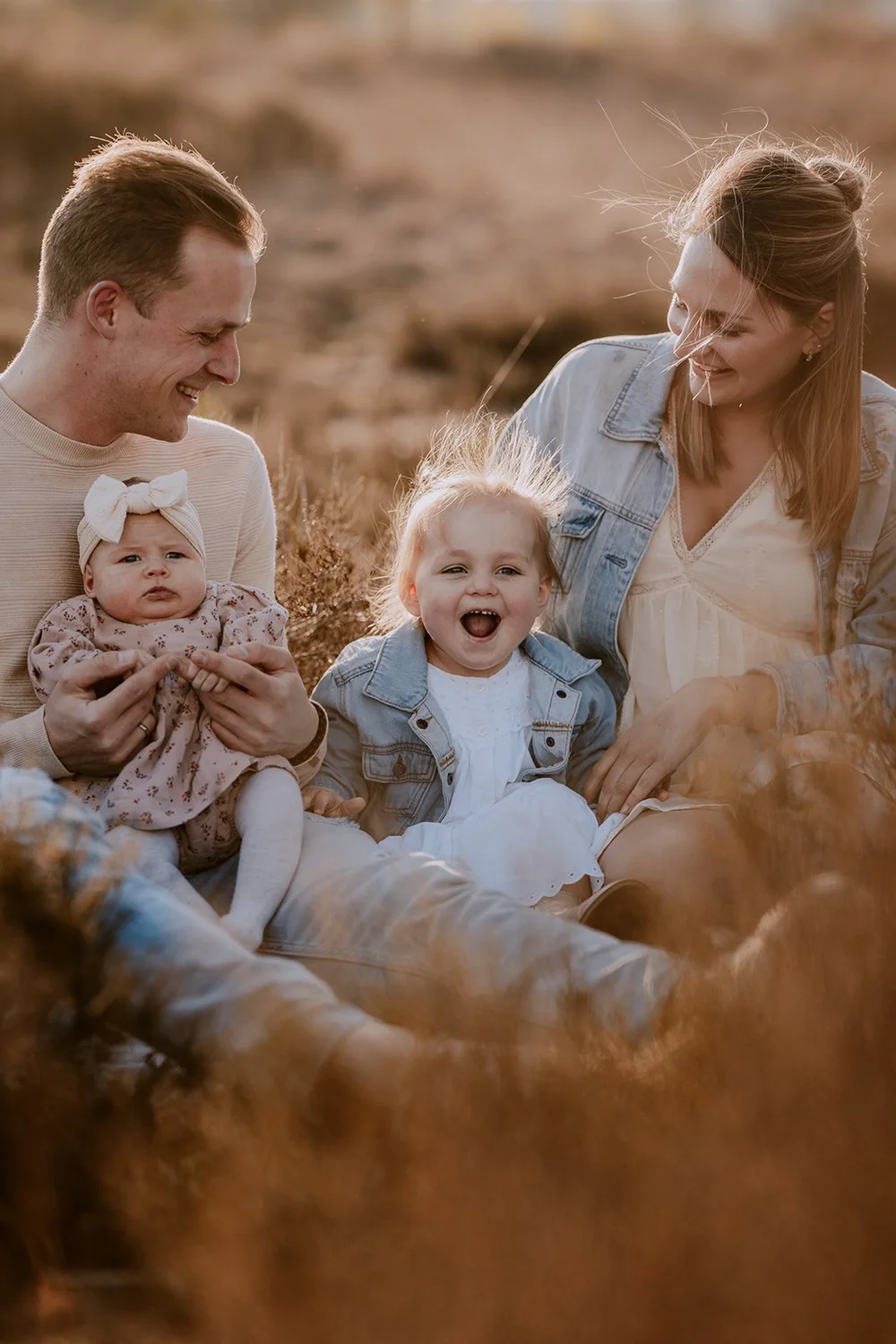 Lachend gezin met baby in het hoge gras