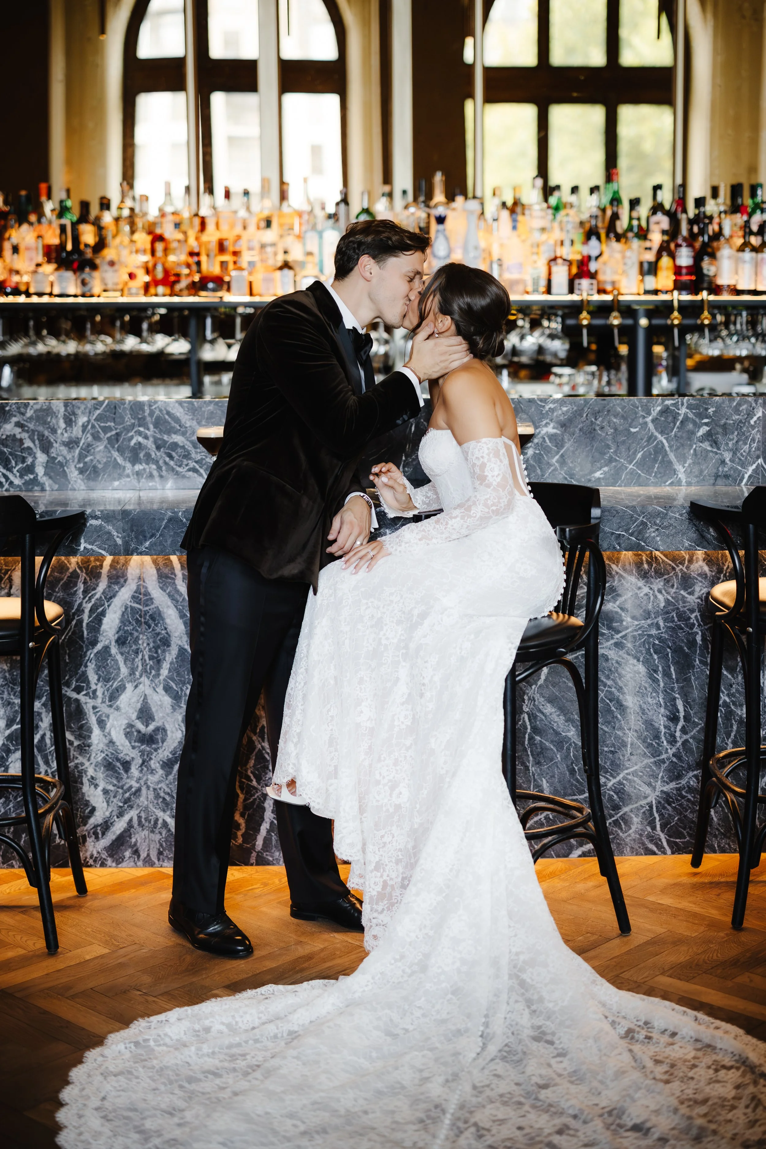 Twee bruid en bruidegom in een romantisch moment bij een bar, kussen in een luxe interieur.