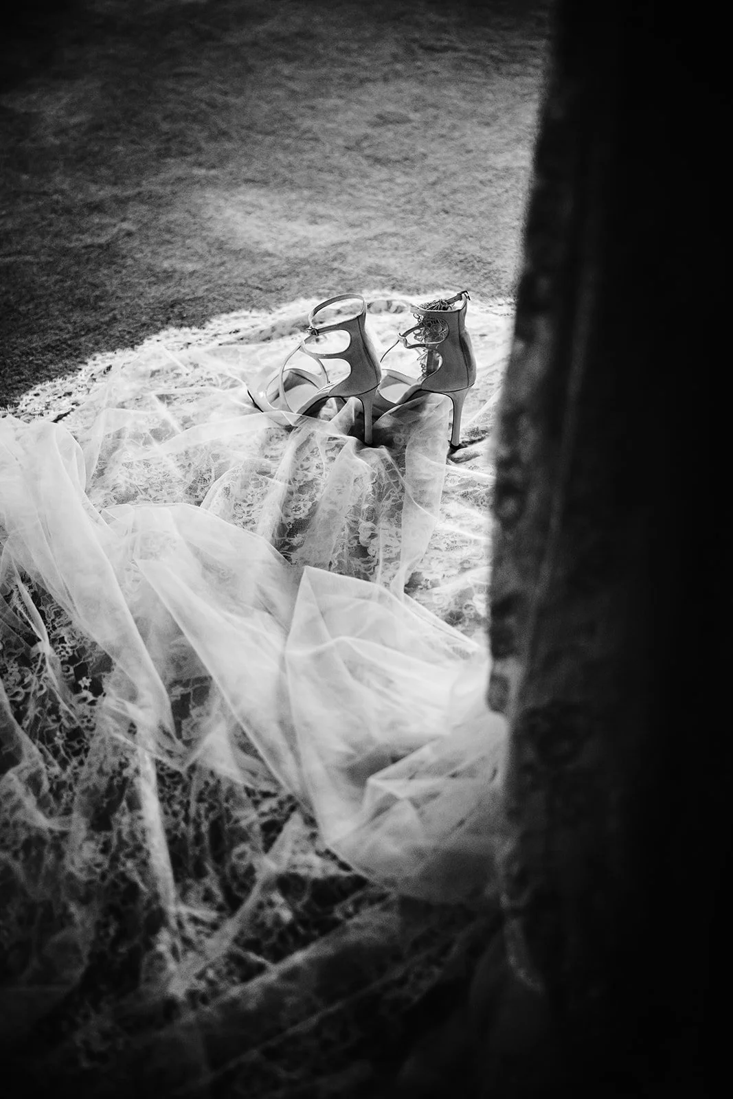 Zwarte en witte hoge hakken schoenen liggen op een lapje kantachtige stof op de vloer.