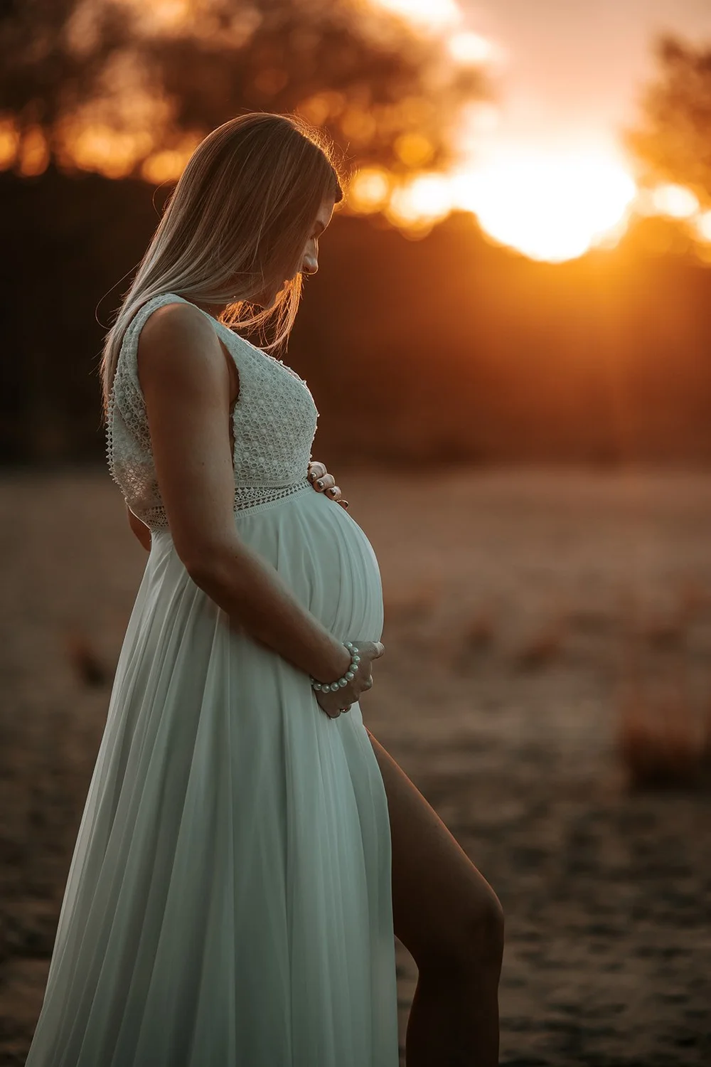 Zwangere vrouw in silhouet bij zonsondergang