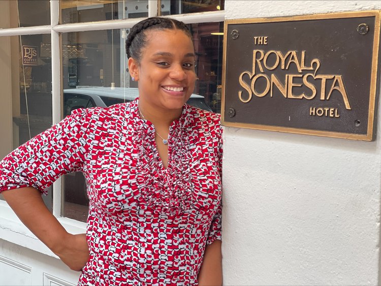 Sarah smiles brightly while standing next to the Royal Sonesta Hotel sign
