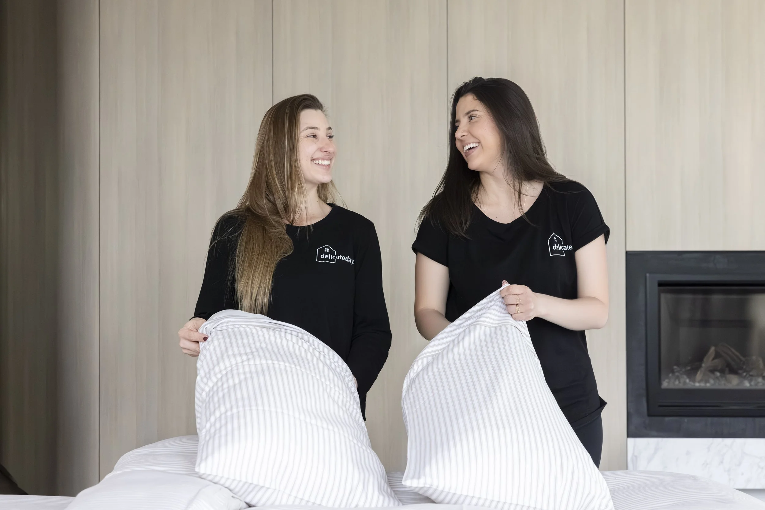 Two women putting sheets on a pillow