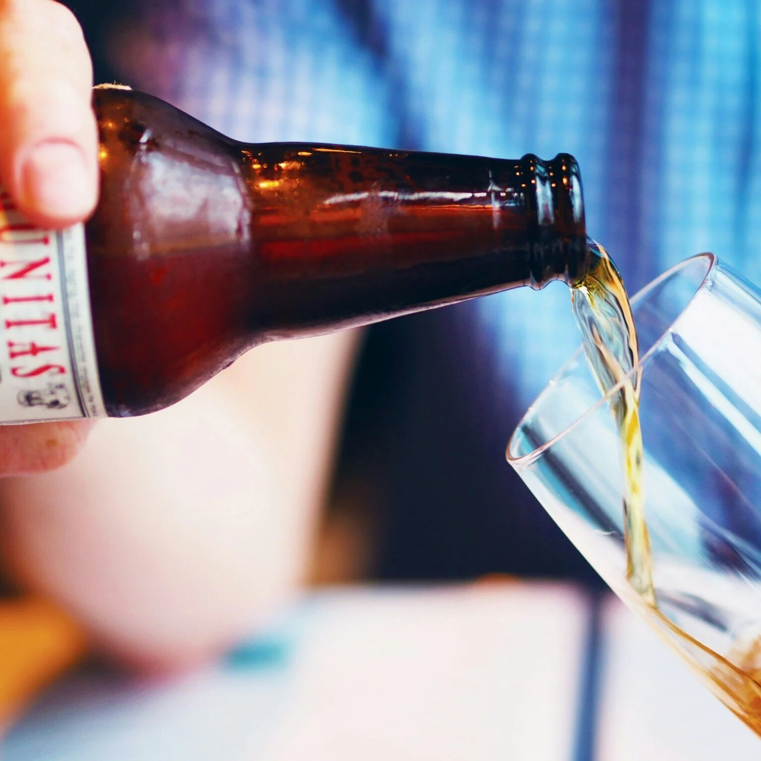 Hand pouring beer from a bottle into a glass
