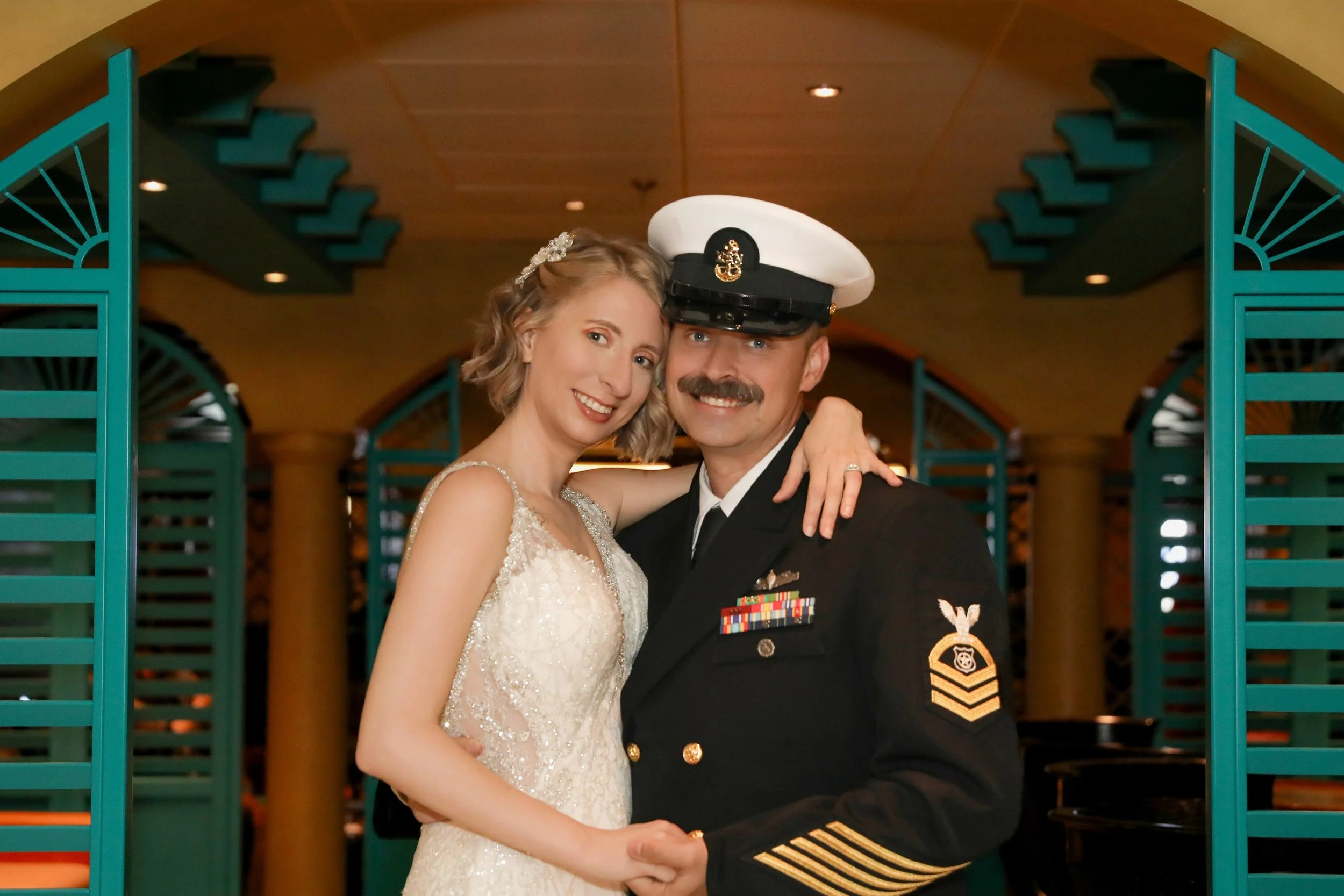 A bride and a navy officer smiling and embracing at a wedding reception.