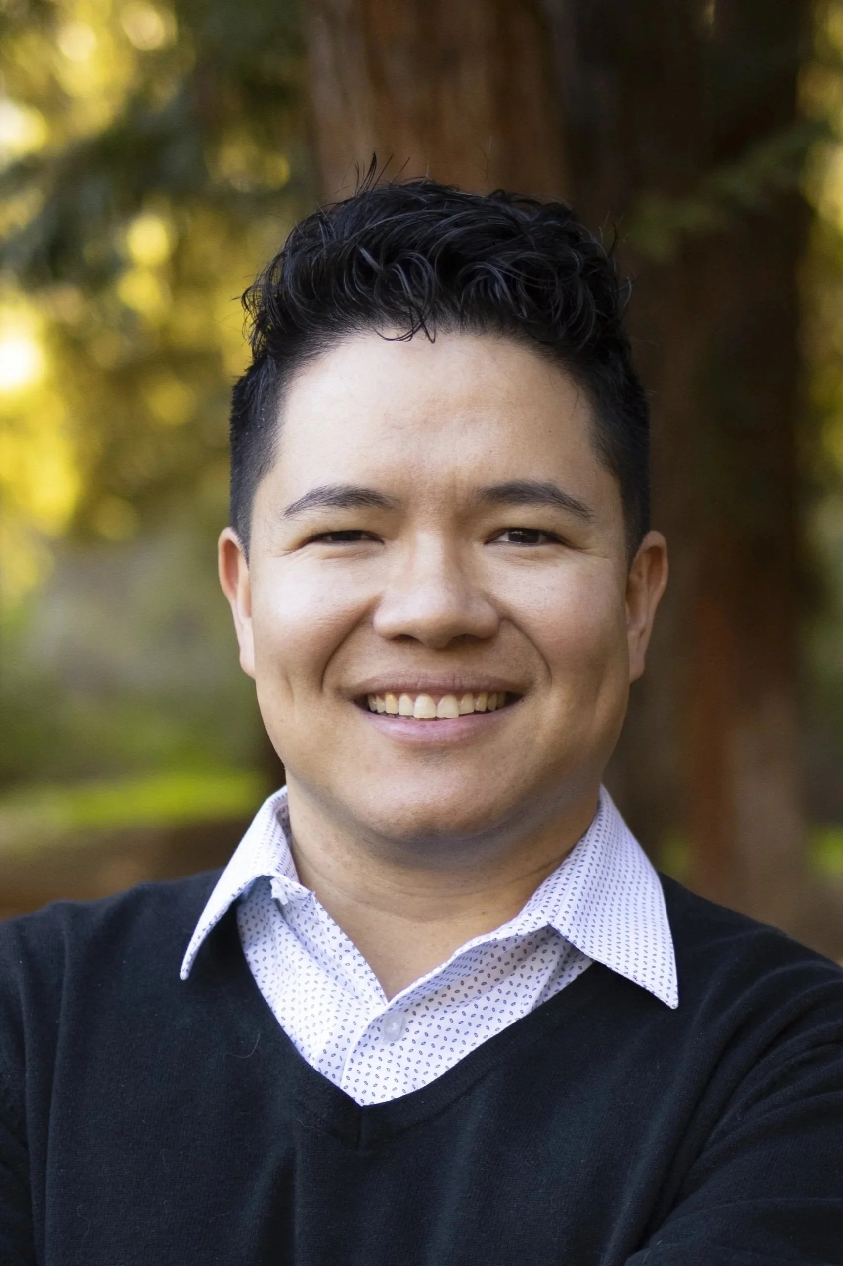 Head shot of Jeremy Logeot, smiling, wearing a collared shirt and sweater