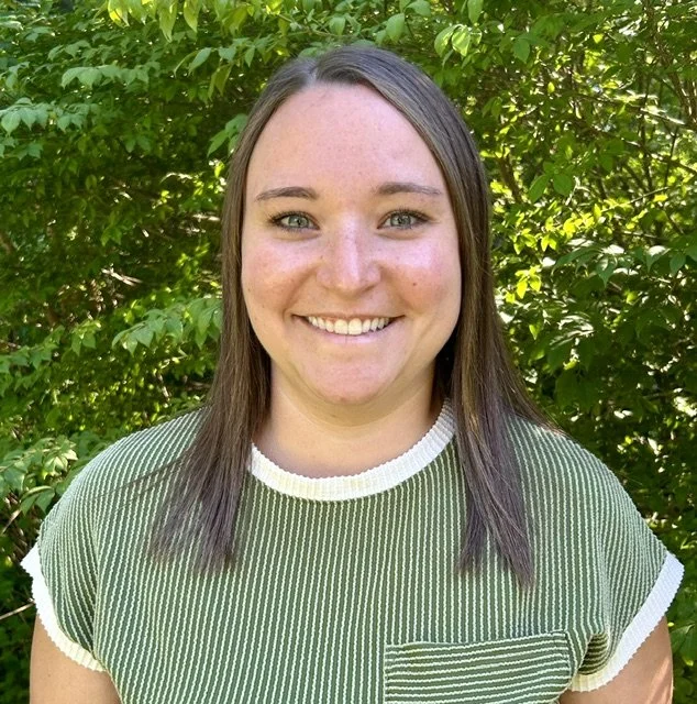 portrait of woman in green striped shirt with foliage background