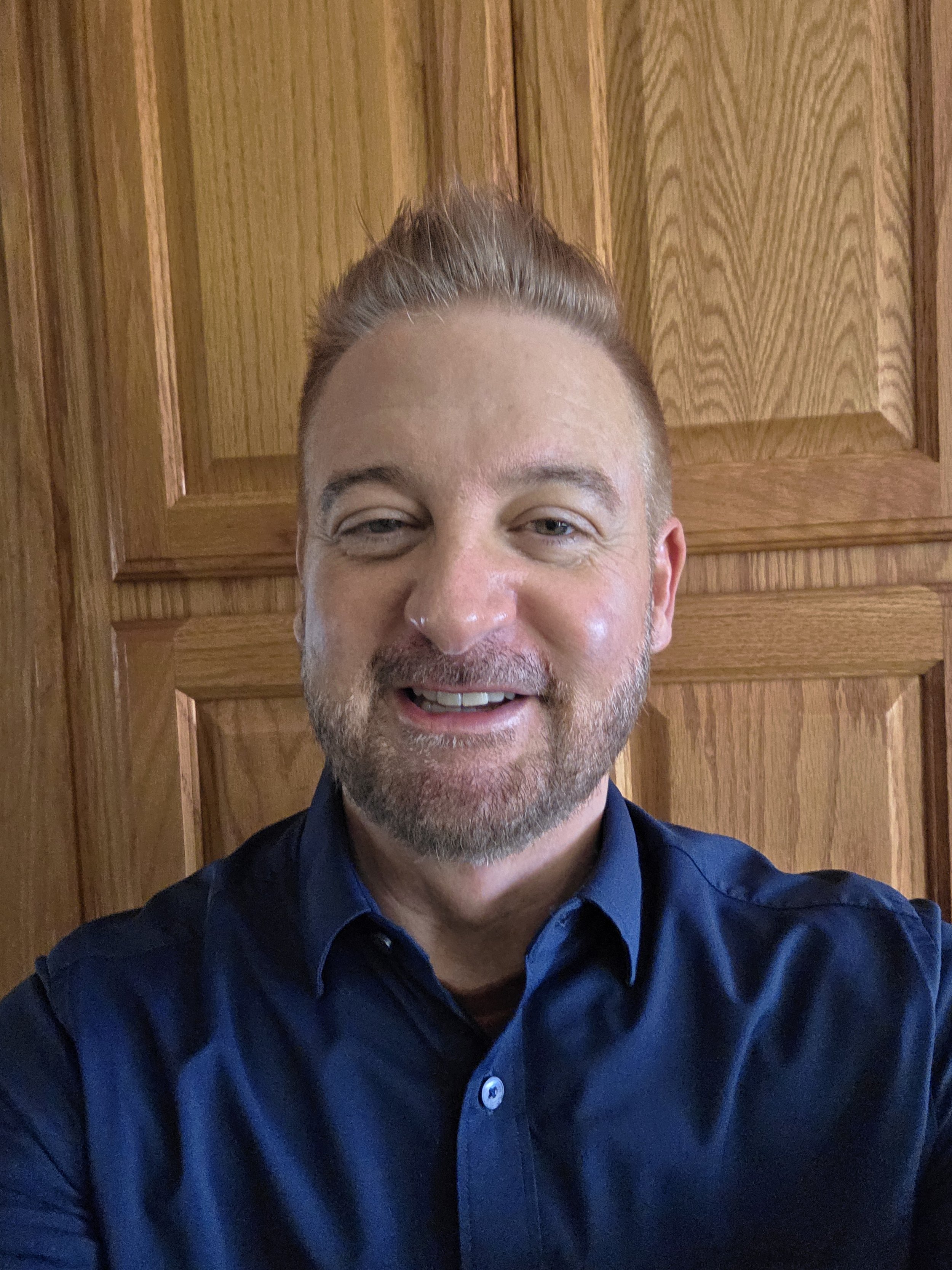 headshot of Scott - blue shirt, beard, light hair