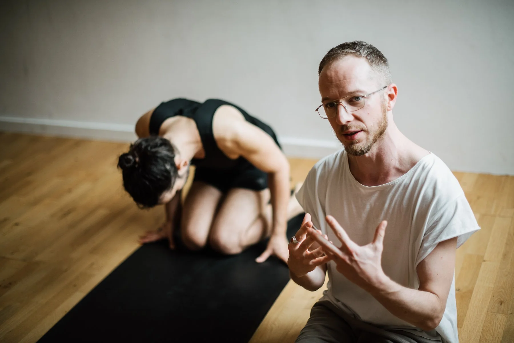 yoga teacher with yoga student in the background