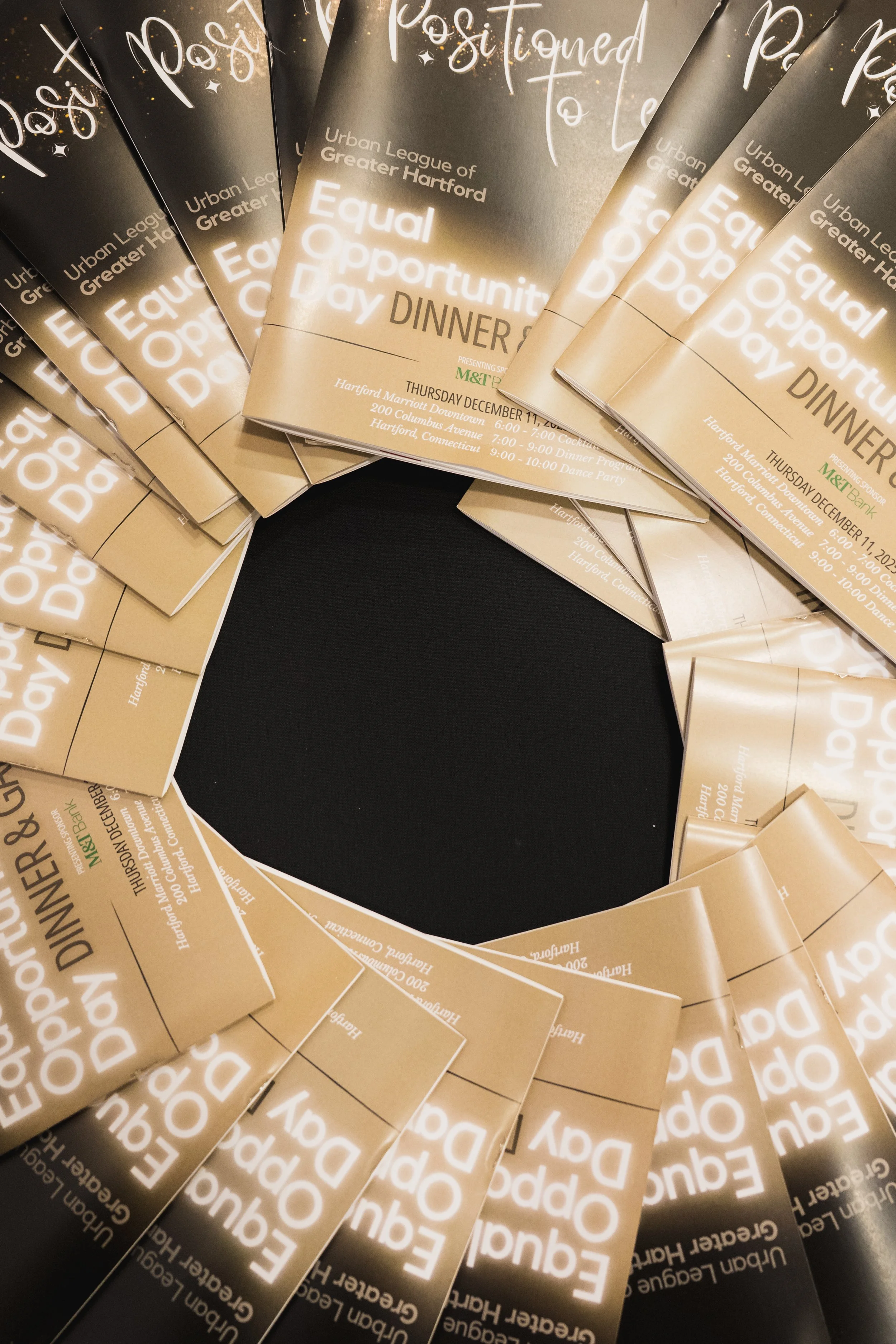 Multiple beige flyers promoting an Equal Opportunity Day Dinner event, arranged in a circular pattern with a black negative space in the middle.