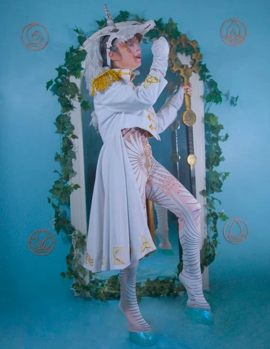 A unicorn dancing in front of a mirrored portal. The portal is edged in ivy and surrounded by wooden element sigils.