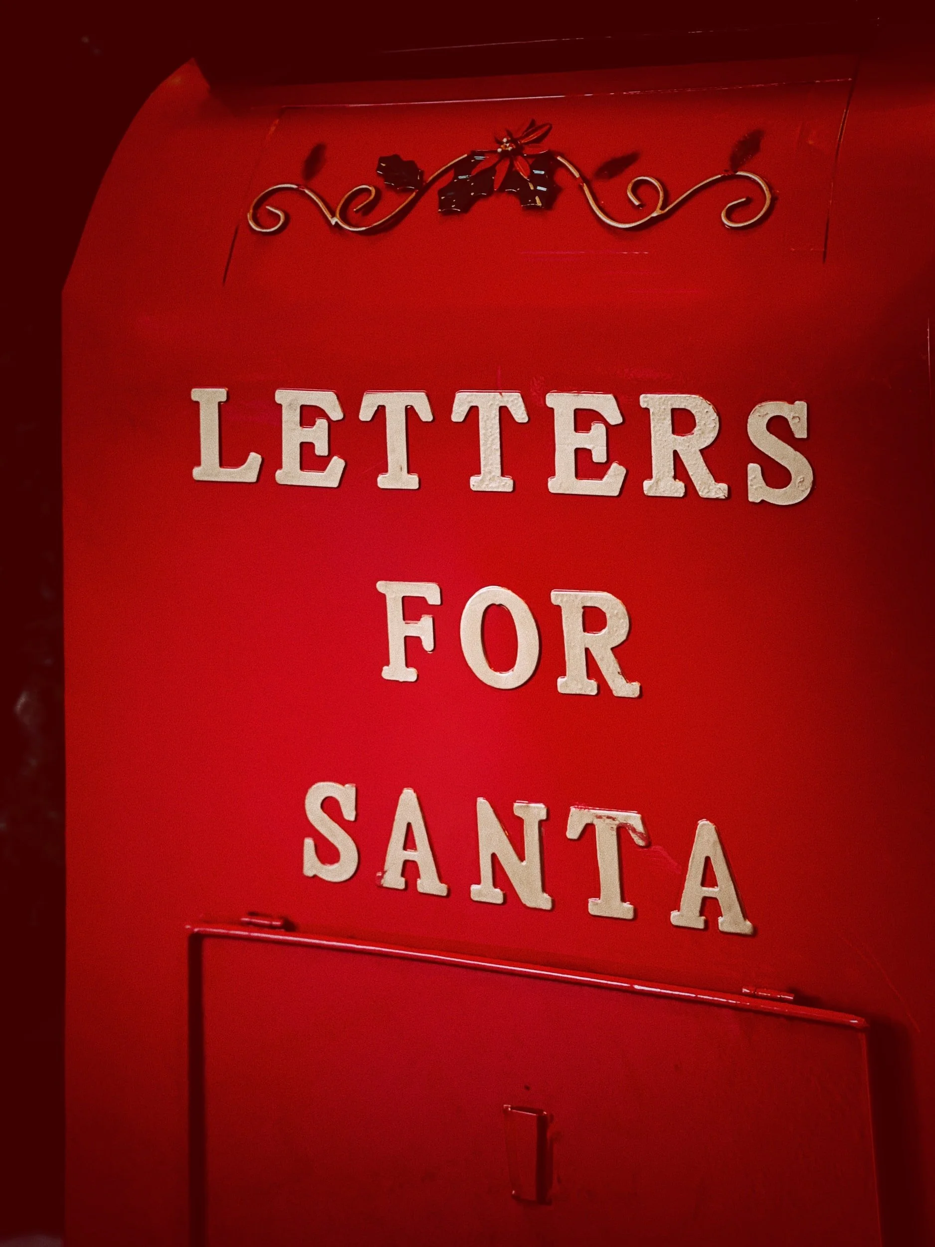 Red mailbox with the words "Letters for Santa" and decorative holly.