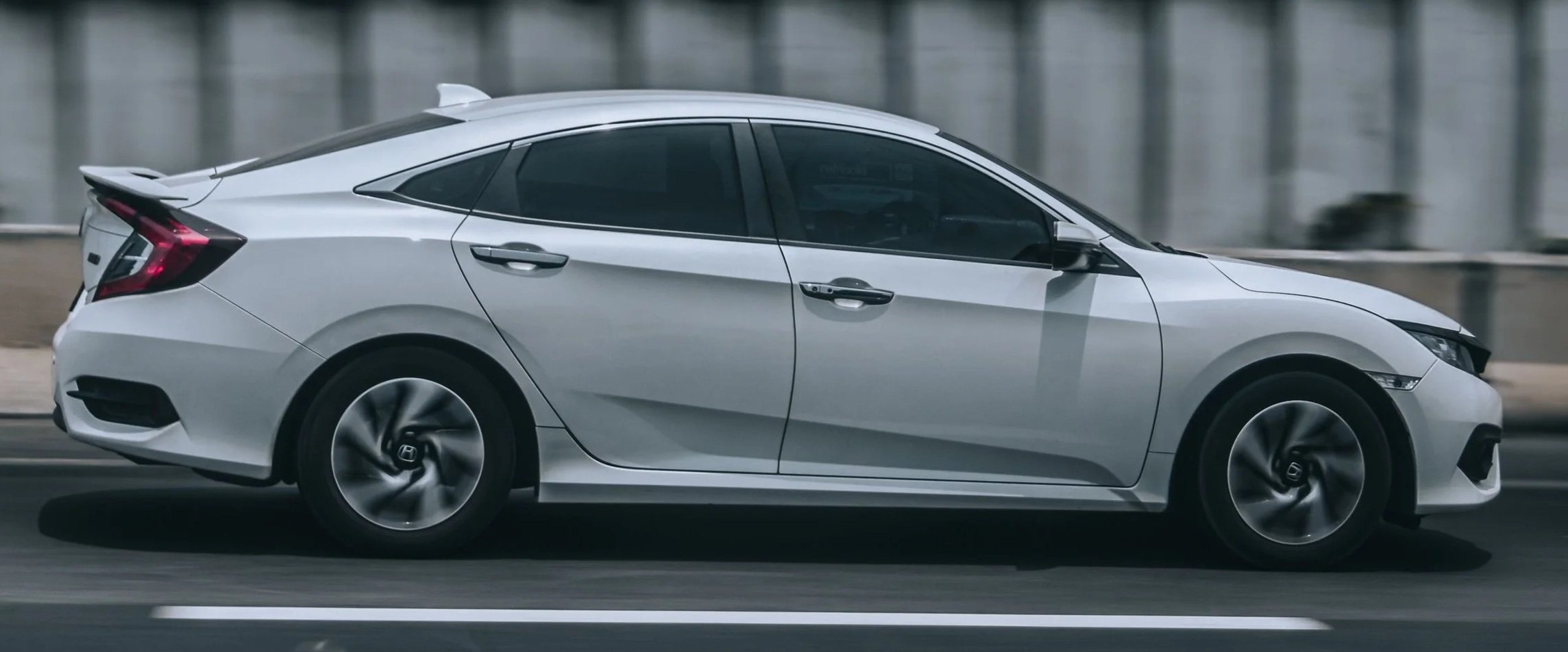 Silver sedan car driving on a road.