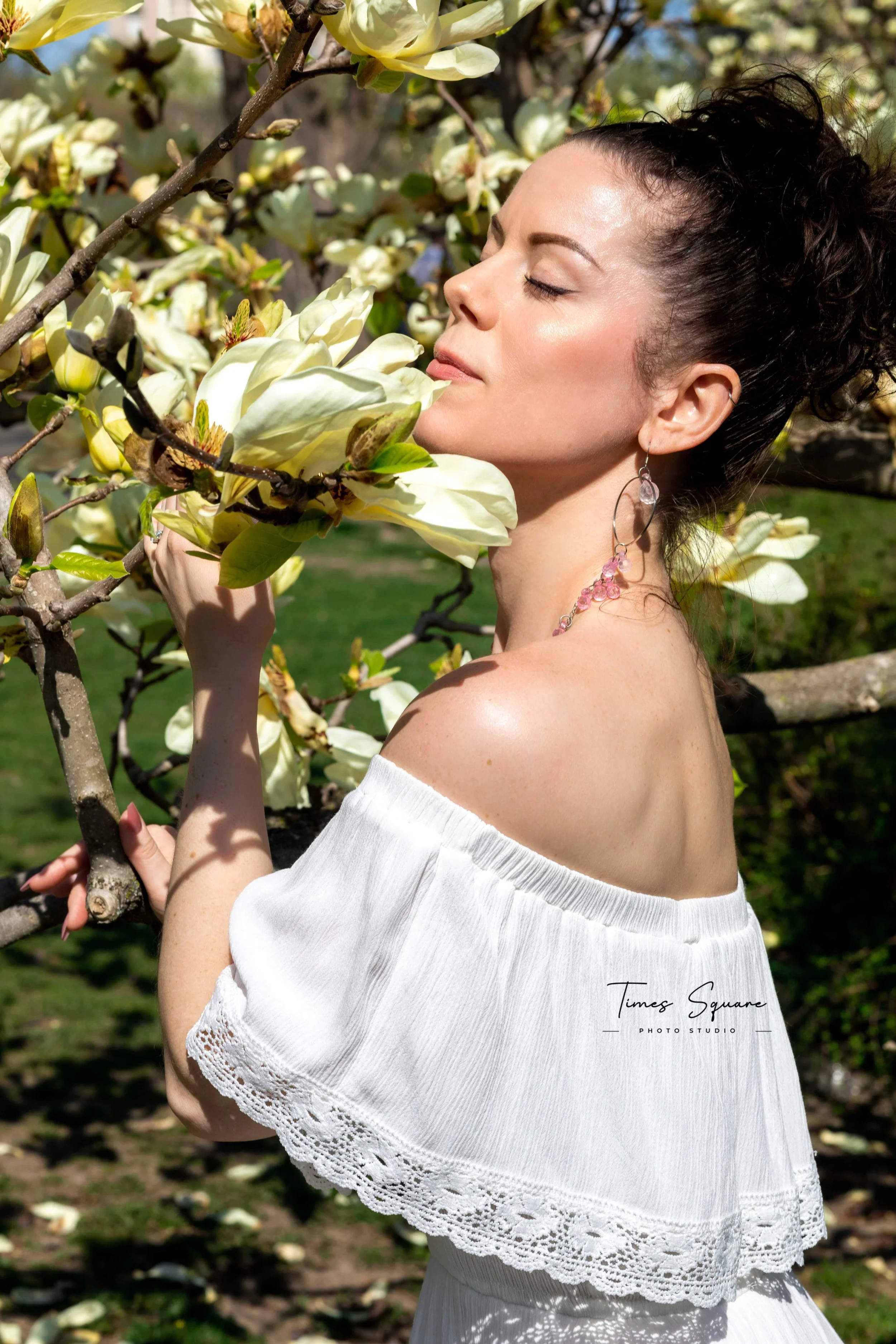 A woman enjoying a spring photoshoot with magnolia blooming trees in Central Park, New York City.