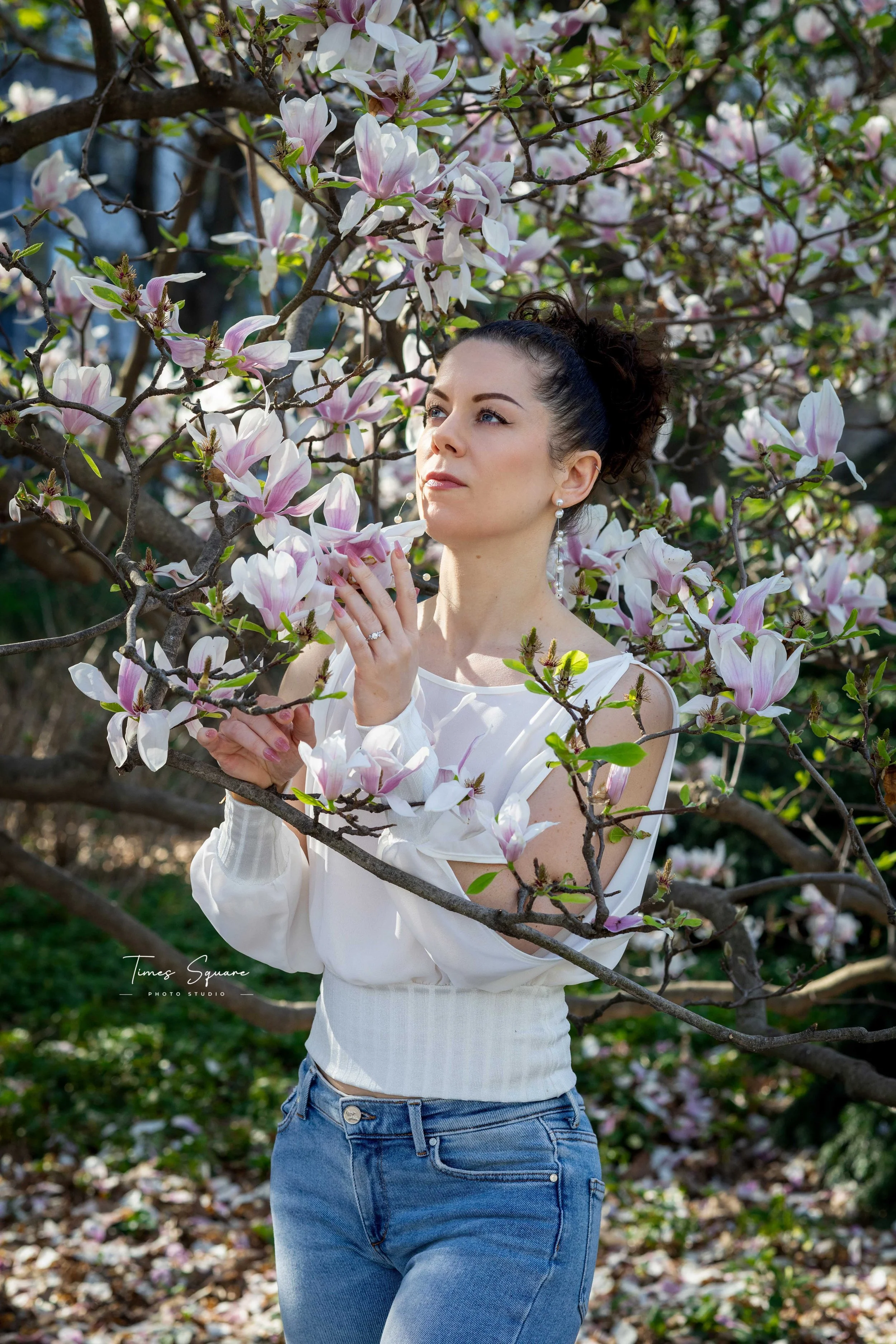 A woman enjoying a spring photoshoot with magnolia blooming trees in Central Park, New York City.
