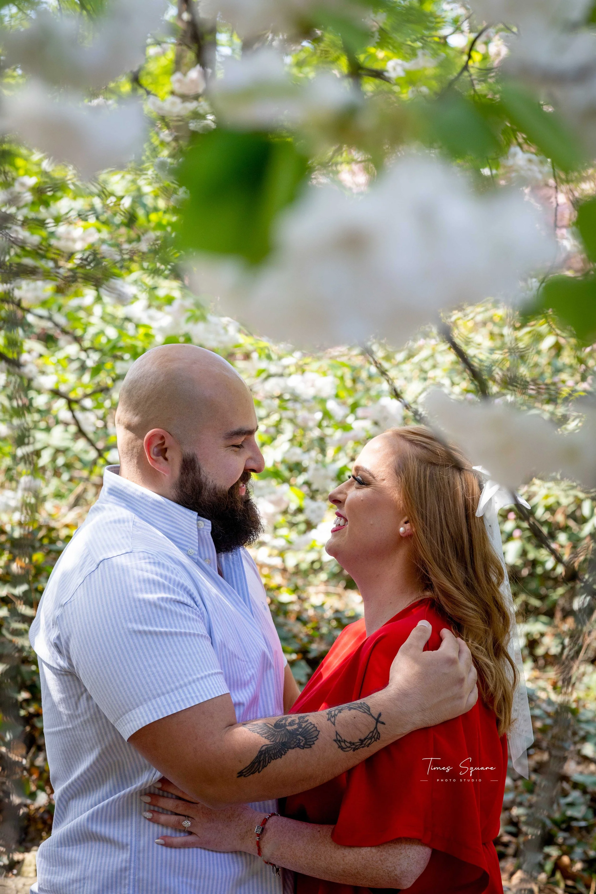 Couple posing under cherry blossoms during a spring engagement photoshoot in Brooklyn Botanic Garden, New York City.